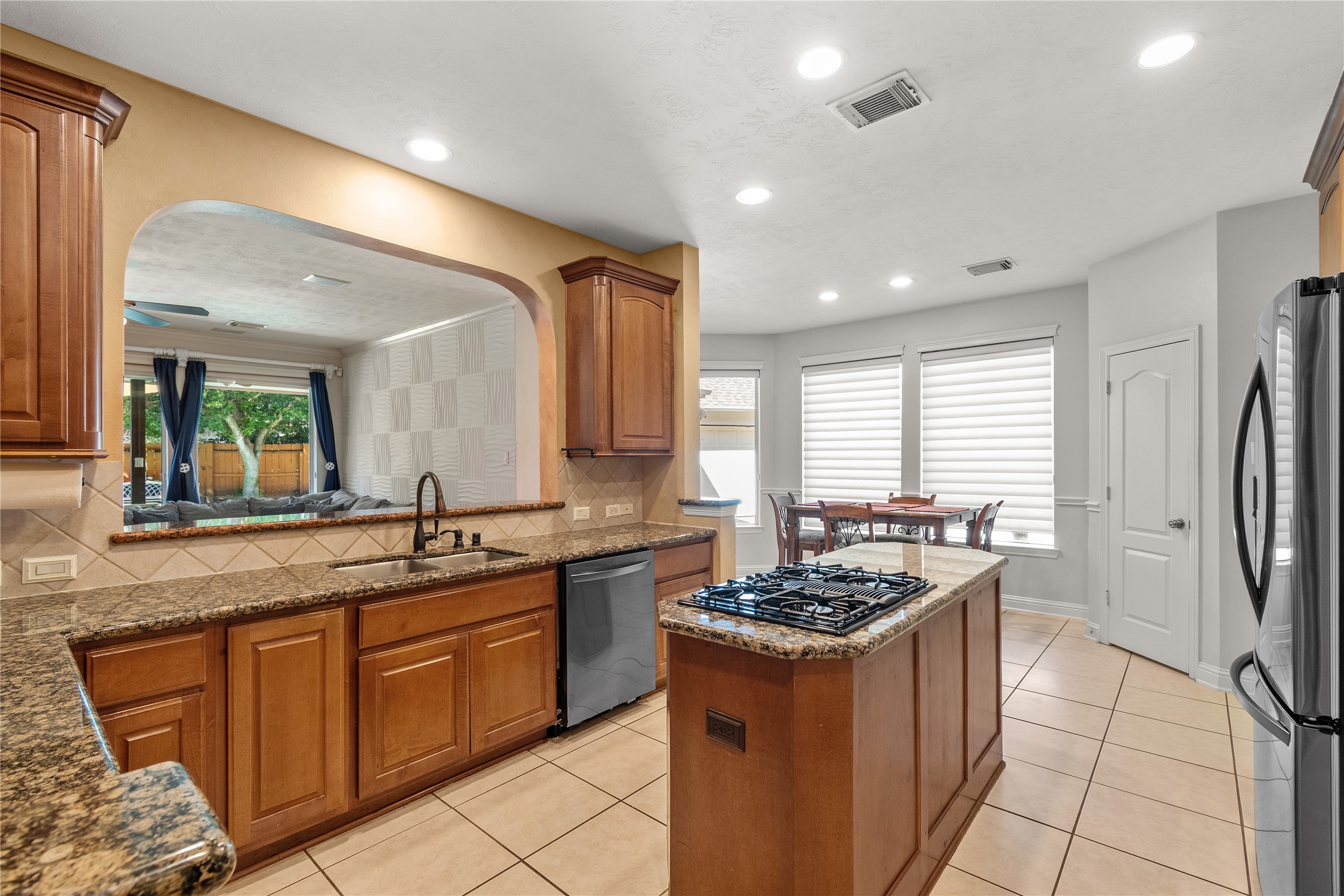 An inviting kitchen with beautiful cabinetry, an island with cooktop and an easy connection to the sunny breakfast area offers plenty of space for cooking, conversation and casual gatherings.