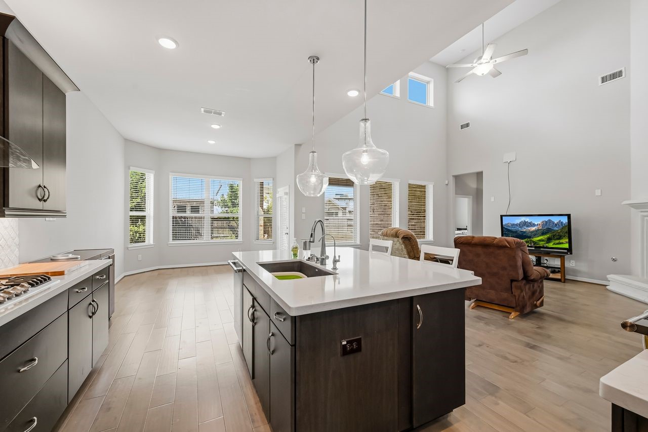 Expansive windows flood the space with natural light, seamlessly connecting the breakfast bay to the living area under the glow of elegant recessed lighting.
