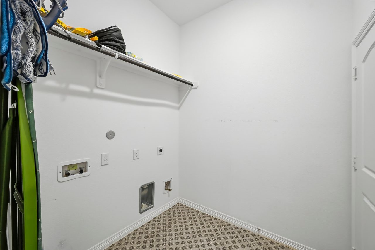 Thoughtfully designed utility space featuring custom built-in shelving and integrated hanging rails for seamless organization. This versatile area is fully equipped to accommodate either a gas or electric dryer.