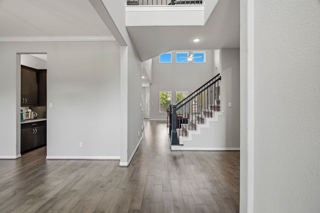 Experience an immediate sense of scale and light in this striking open-concept entryway. Soaring ceilings and a sophisticated staircase anchor the space, while expansive windows bathe the crisp palette and warm wood flooring in natural radiance. The layout flows effortlessly, offering a seamless transition toward the kitchen and breakfast area or providing convenient access to the private study and utility wing. Experience an immediate sense of scale and light in this striking open-concept entryway. Soaring ceilings and a sophisticated staircase anchor the space, while expansive windows bathe the crisp palette and warm wood flooring in natural radiance. The layout flows effortlessly, offering a seamless transition toward the kitchen and breakfast area or providing convenient access to the private study and utility wing.