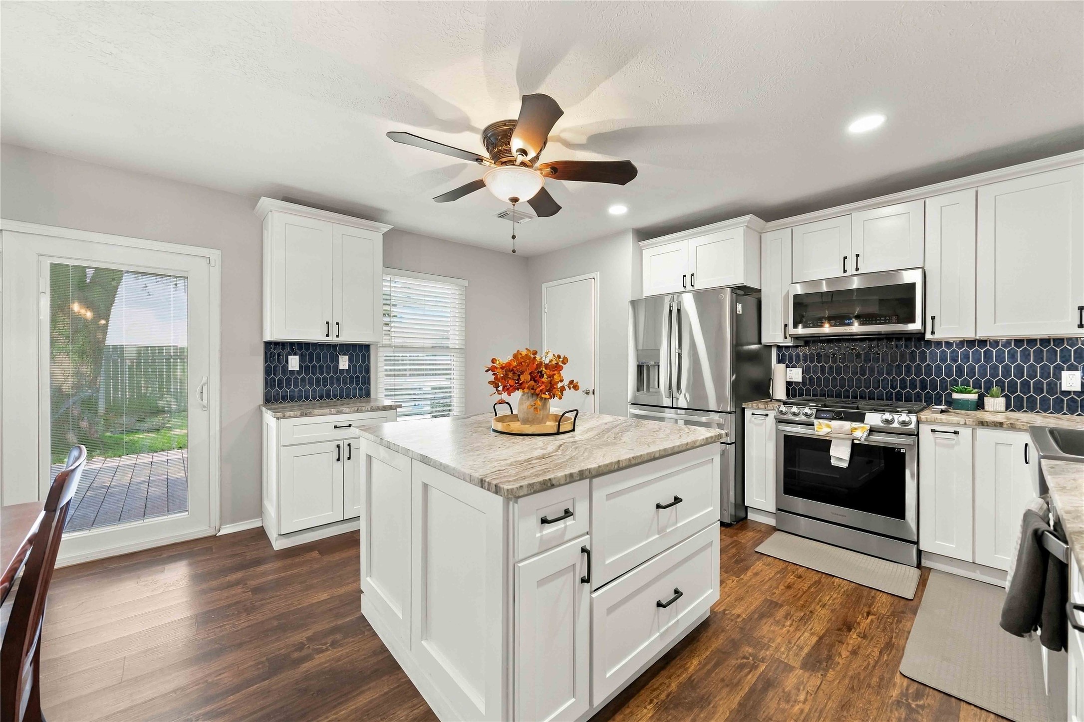 Well-appointed kitchen showcases a generous center island, shaker-style cabinetry, stainless-steel appliances, and a striking tile backsplash.