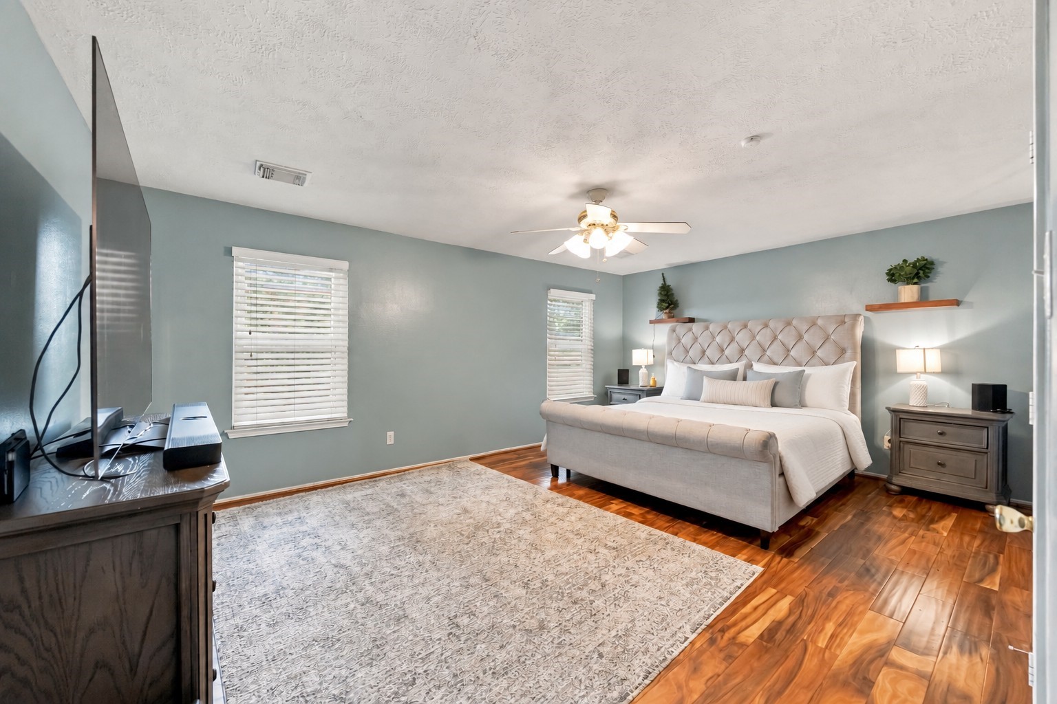 Expansive primary bedroom features abundant floor space, multiple windows, wood flooring, and direct access to the adjoining bath and closet areas.