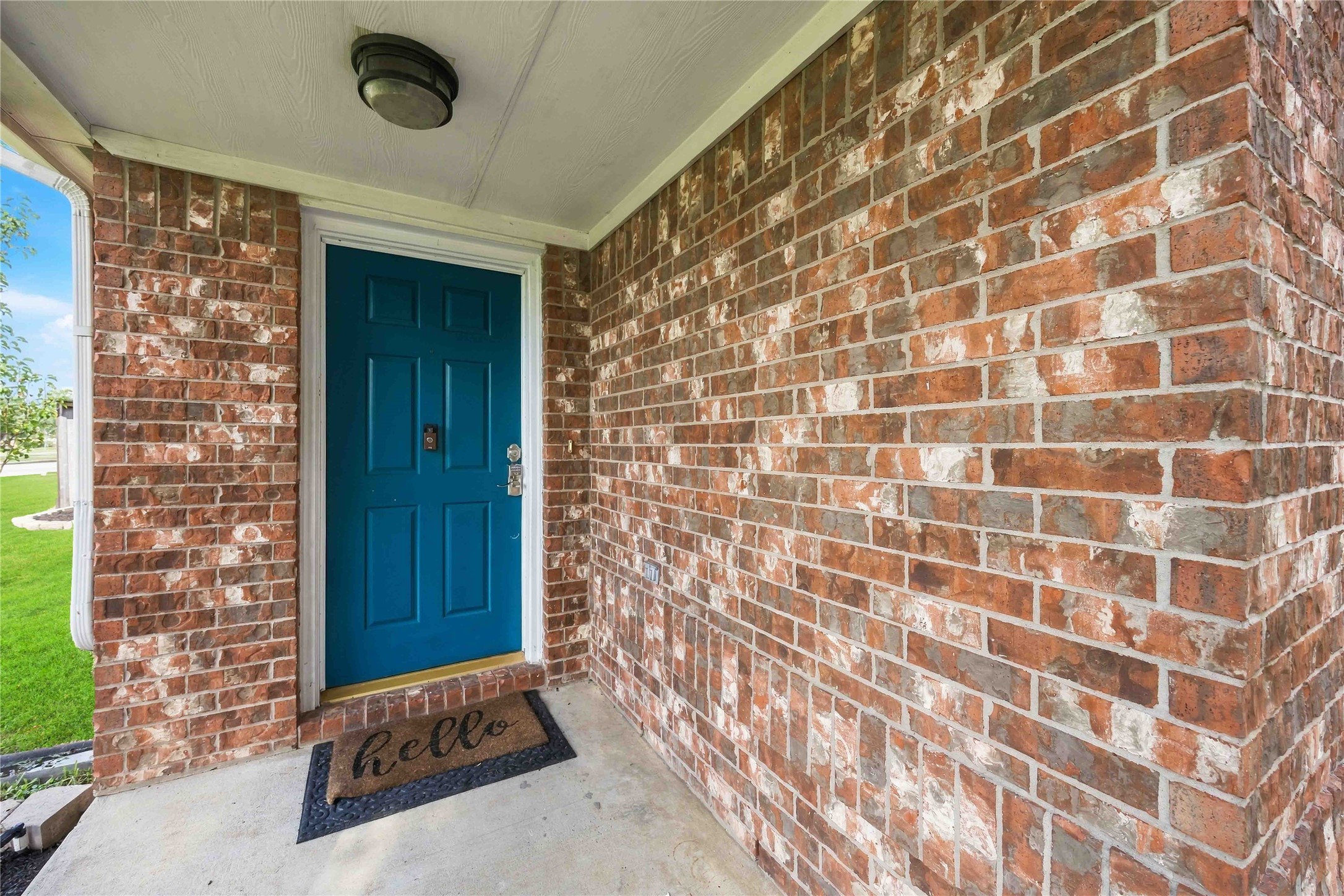 Covered front porch accented by a distinctive blue entry door and classic brick exterior.