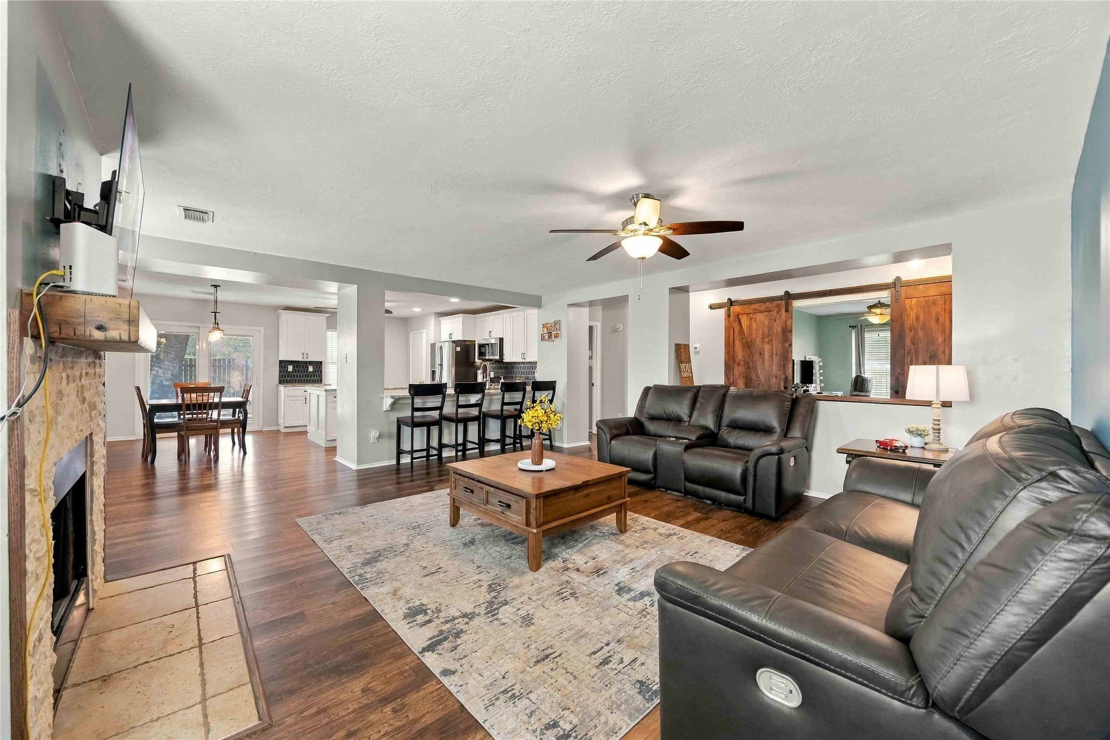 Spacious open living area with a stone fireplace, breakfast bar, and easy flow into the kitchen and dining area.