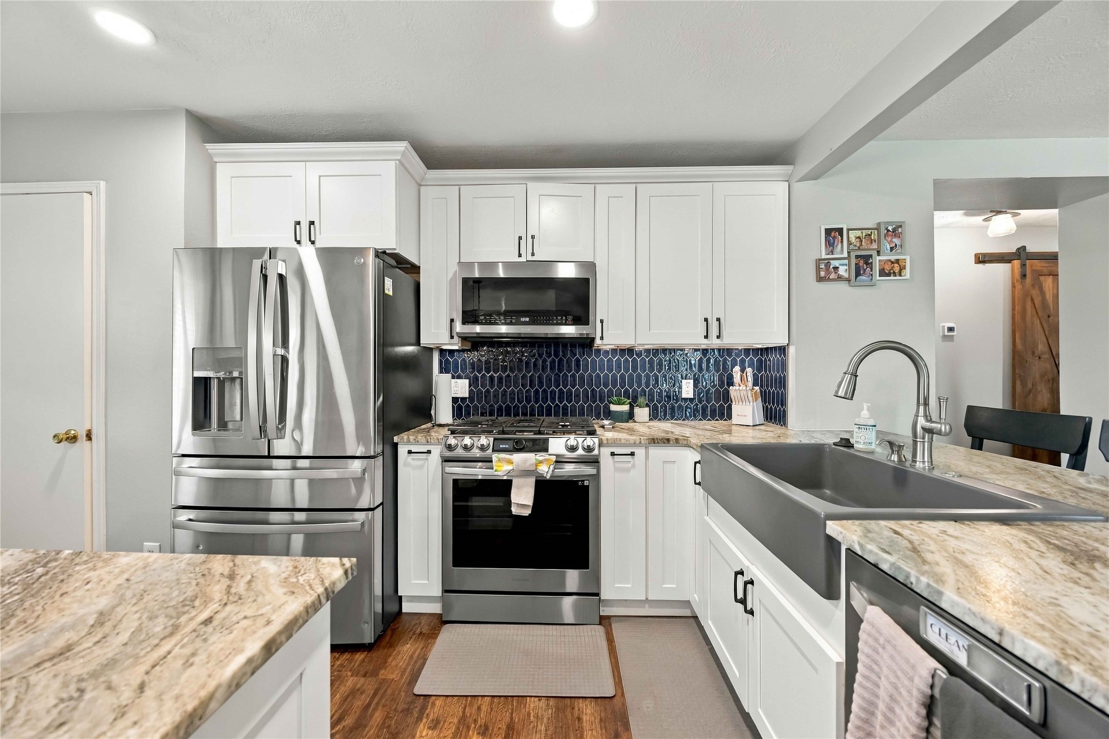Updated kitchen features extensive cabinetry, stainless-steel appliances, a farmhouse-style sink, and contrasting tile backsplash.