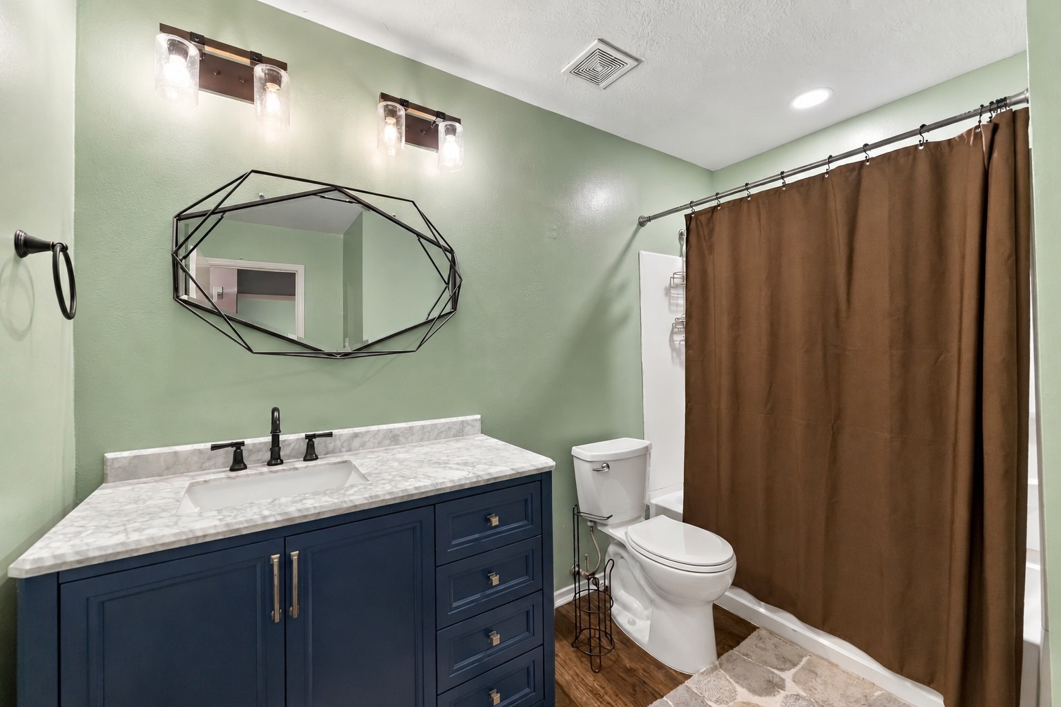 Full secondary bathroom features a spacious vanity, updated fixtures, and a tub-shower combination.