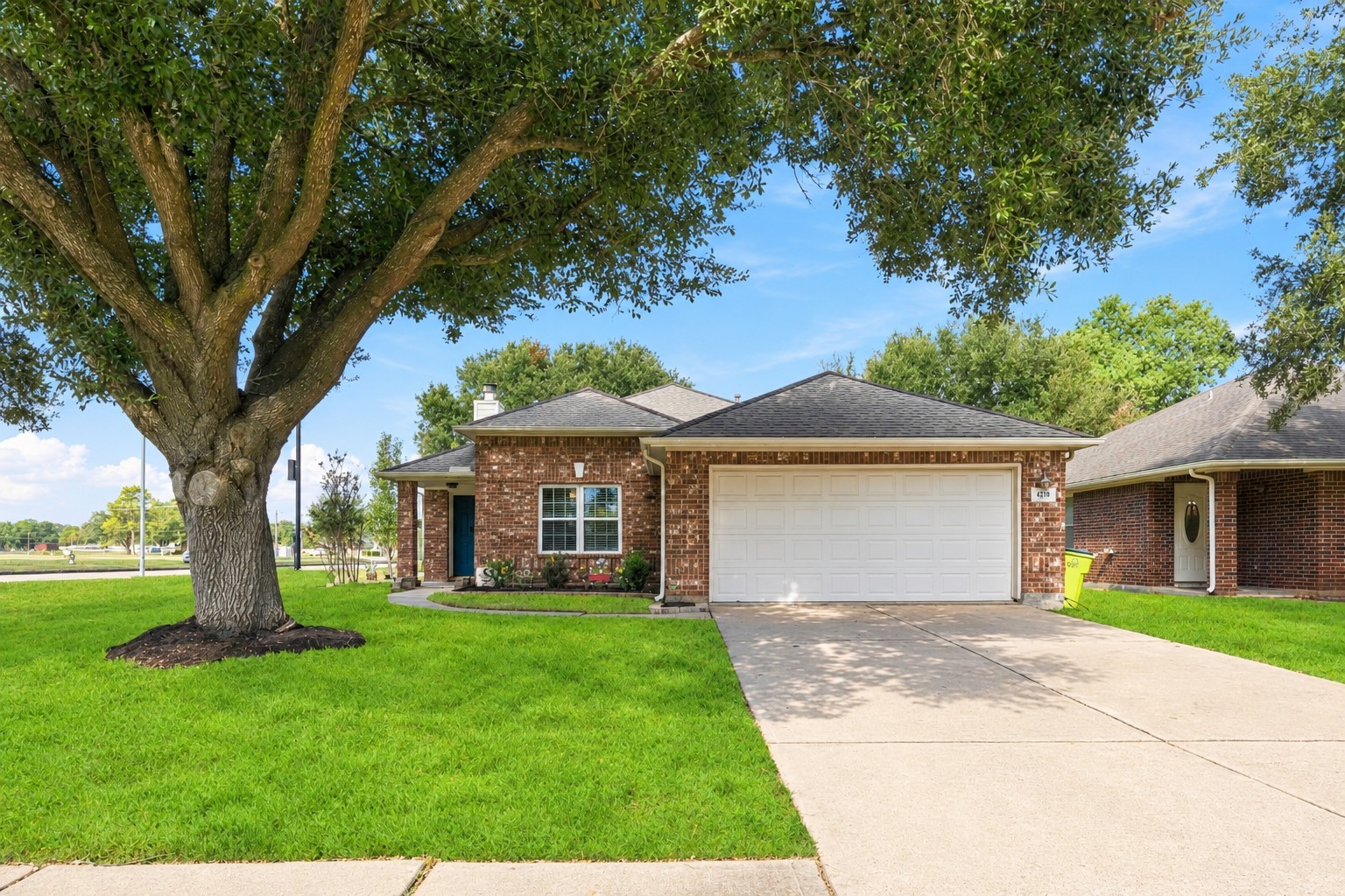 Classic brick exterior framed by mature trees, a broad front lawn, and an attached two-car garage.