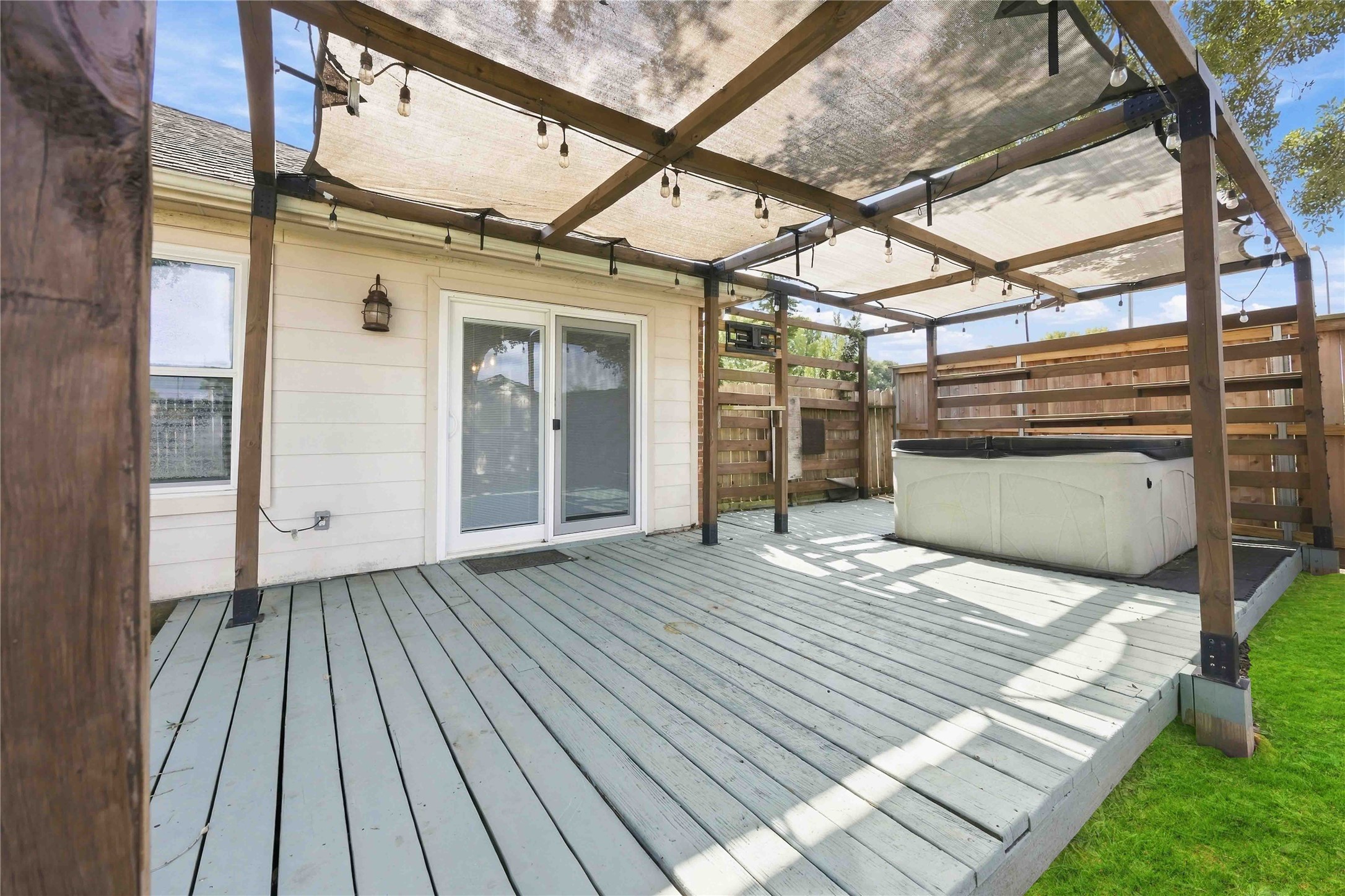 Spacious backyard deck with a pergola-style cover creates a substantial outdoor retreat with room for lounging and recreation.