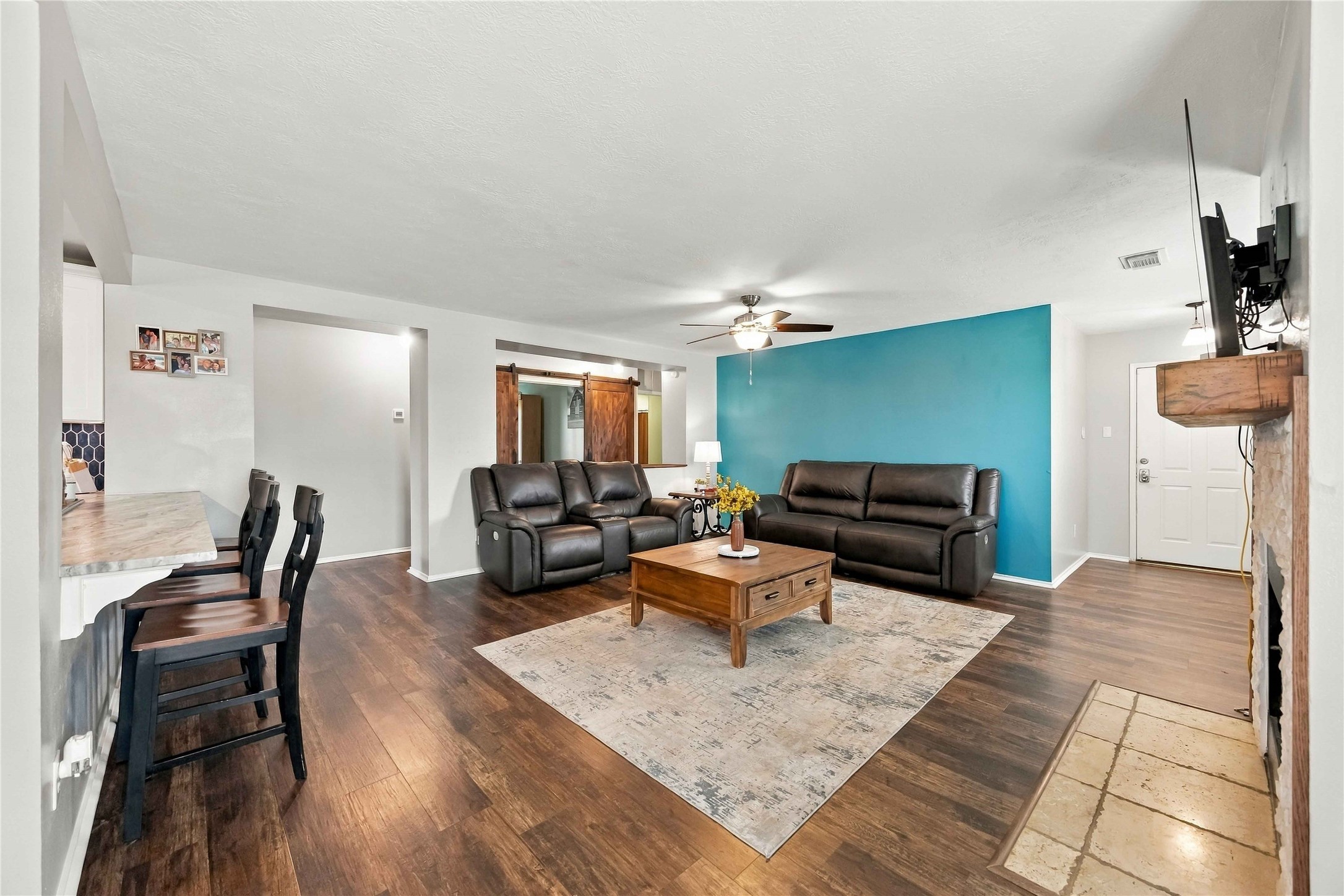 Open-concept living space highlighted by a bold accent wall, breakfast bar seating, and sliding barn doors.