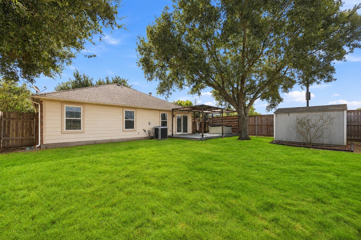 Wide rear view showcases the large fenced yard, mature landscaping, storage shed, and deck extending from the home.