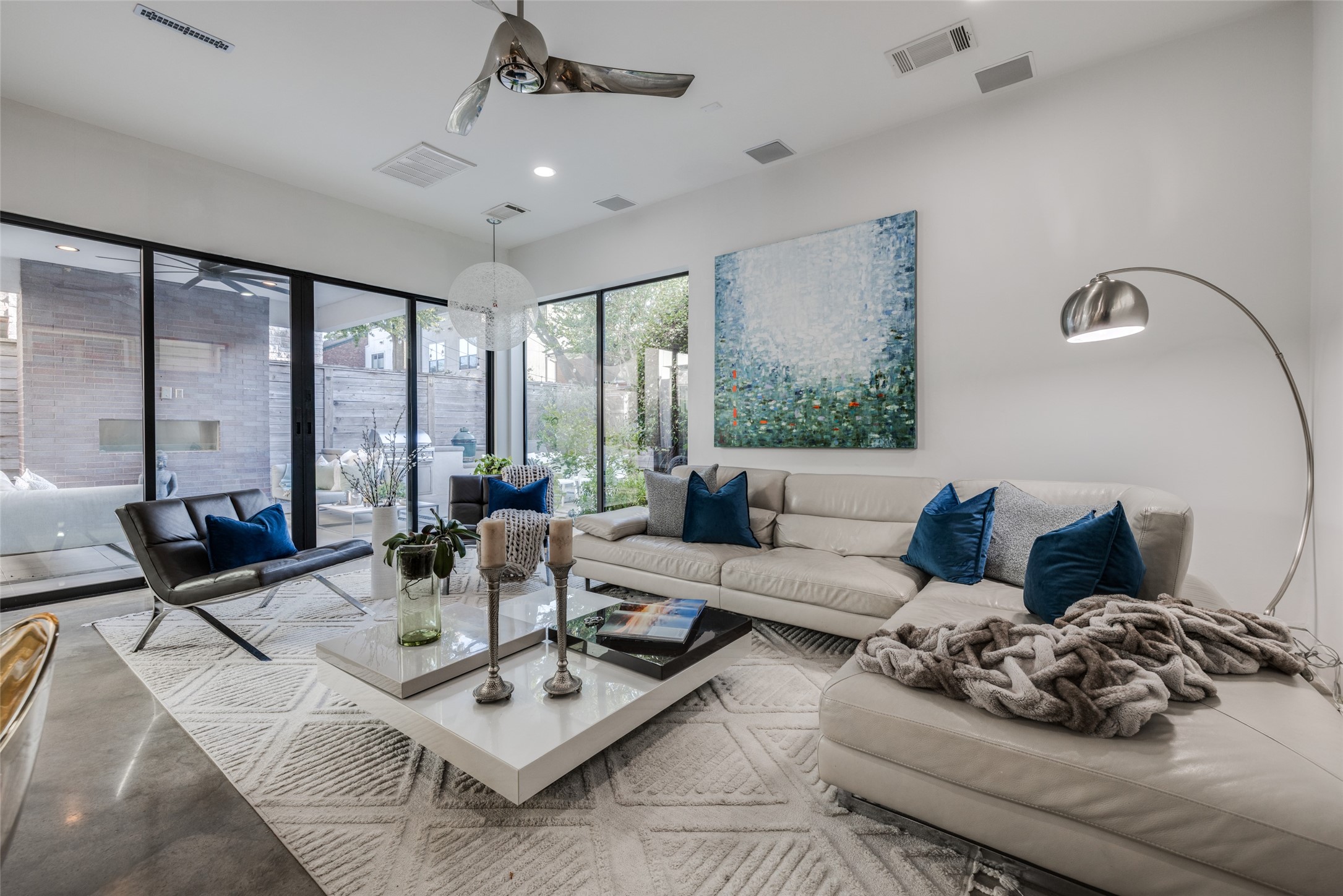 Spacious Living Room with walls of windows & sliding glass doors bringing the outdoors in, easy to maintain modern concrete floors, Minka Aire ceiling fan, LED recessed lights, in ceiling speakers Spacious Living Room with walls of windows & sliding glass doors bringing the outdoors in, easy to maintain modern concrete floors, Minka Aire ceiling fan, LED recessed lights, in ceiling speakers
