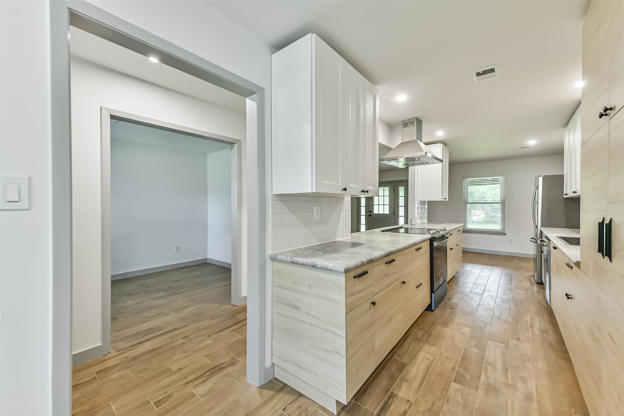 The kitchen boasts a modern design with light wood cabinetry, stainless steel appliances, and a spacious layout.