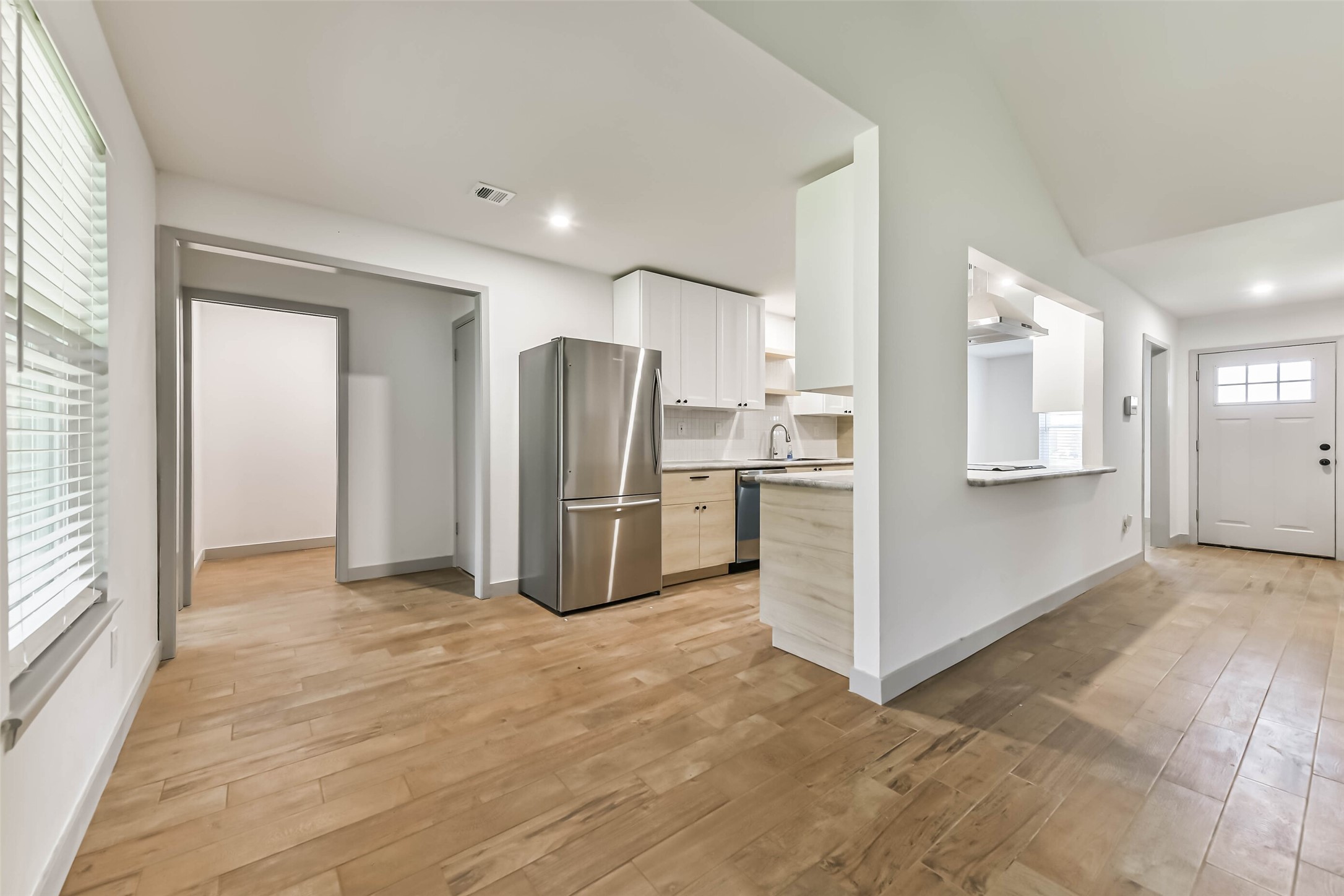 The kitchen features modern stainless steel appliances, white cabinetry, and a bar counter.