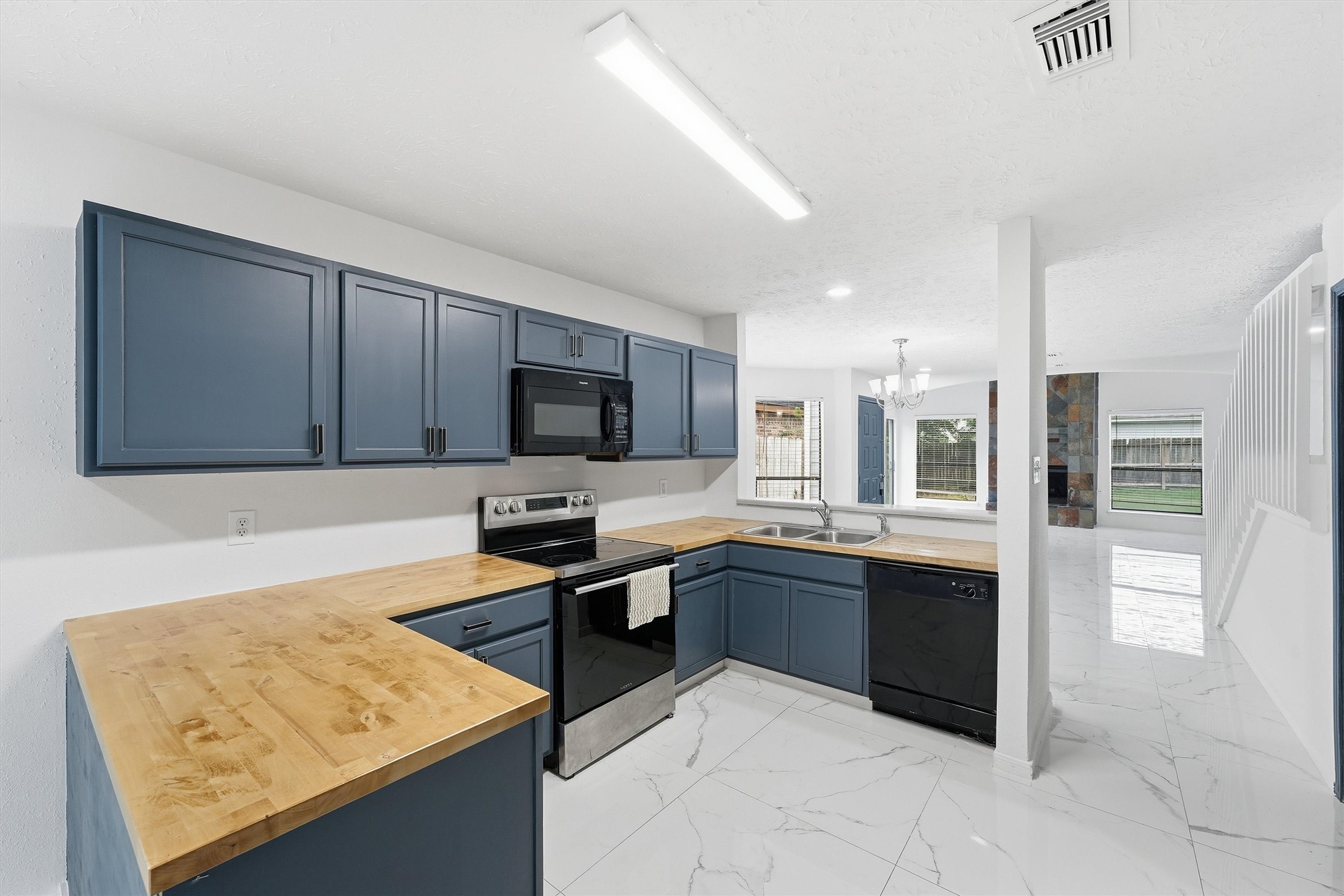 Kitchen brings together blue cabinetry, wood-look countertops, a breakfast bar, and easy access to the dining areas.