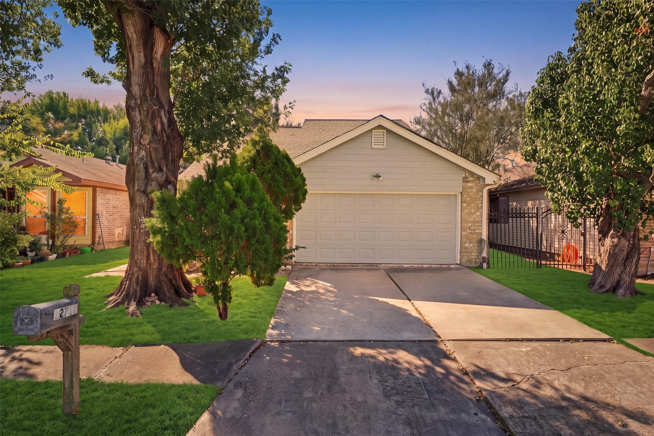 Mature trees frame the home's inviting exterior, complemented by a green front lawn and a paved driveway.