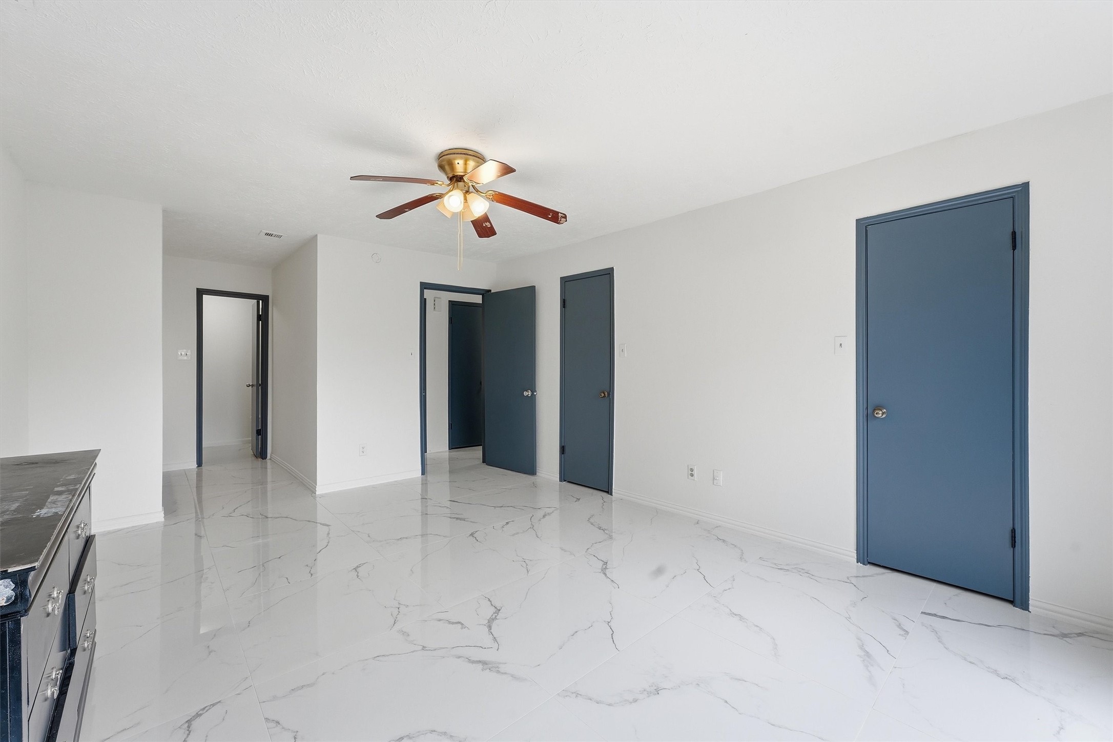 Spacious primary bedroom opens to the backyard through sliding glass doors, complemented by marble-look tile flooring.