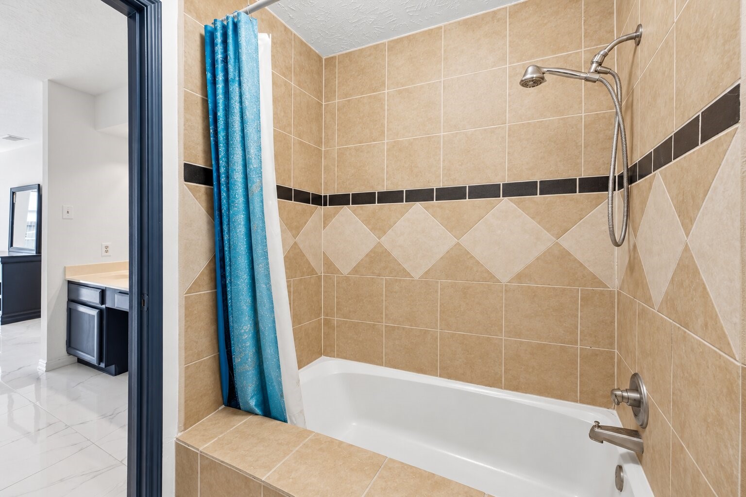 Primary bath includes a double-sink vanity, wide mirror, and tub-shower combination surrounded by decorative tile walls.