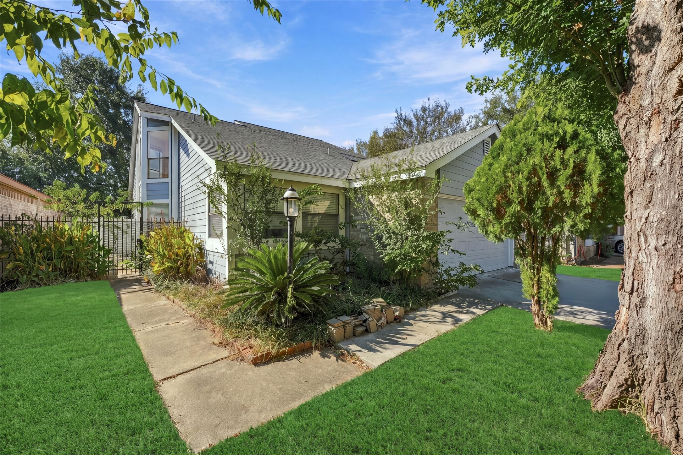Backyard includes a curved walkway, mature trees, and established landscaping, adding greenery and shade to the outdoor space.