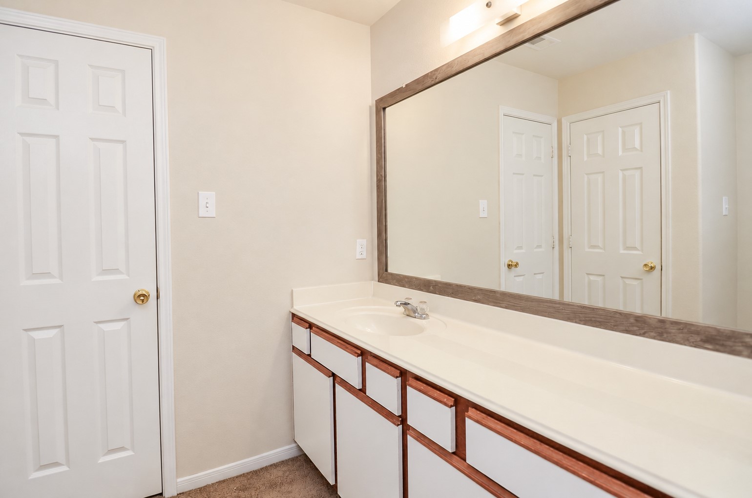 Additional view of the upstairs bathroom showcasing the extended vanity, generous counter space and large framed mirror.
