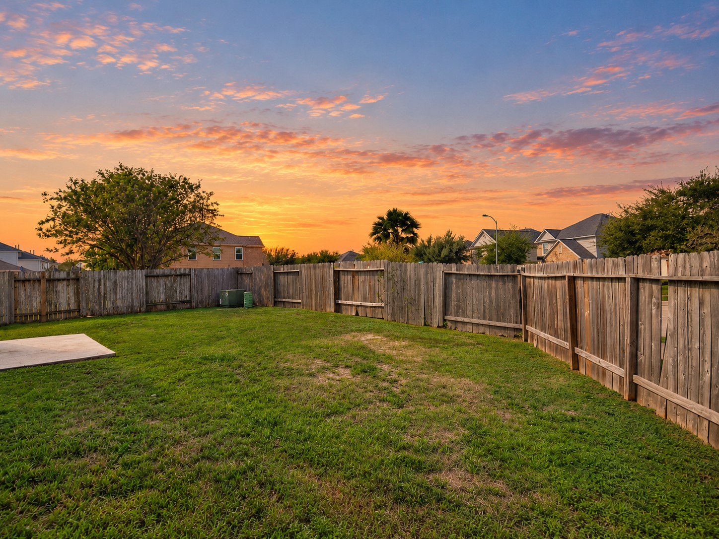 Additional backyard view highlighting the generous lawn, privacy fencing and beautiful evening sky.