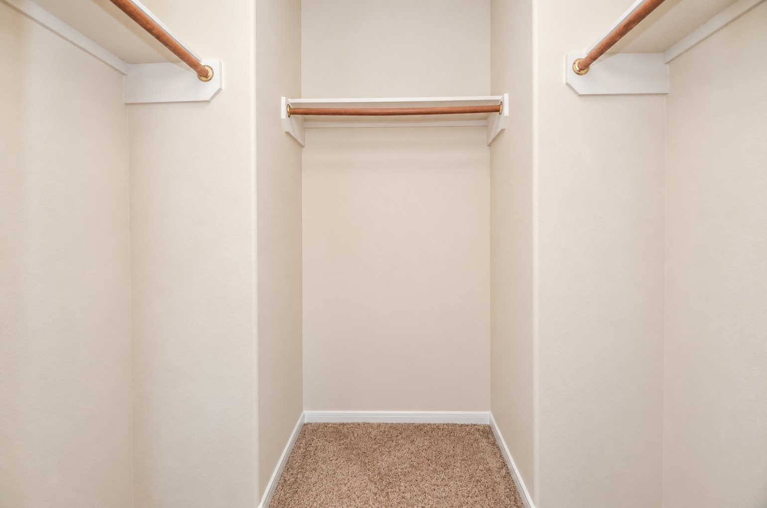 Walk-in closet featuring multiple hanging rods and shelving, providing generous storage and organization options.