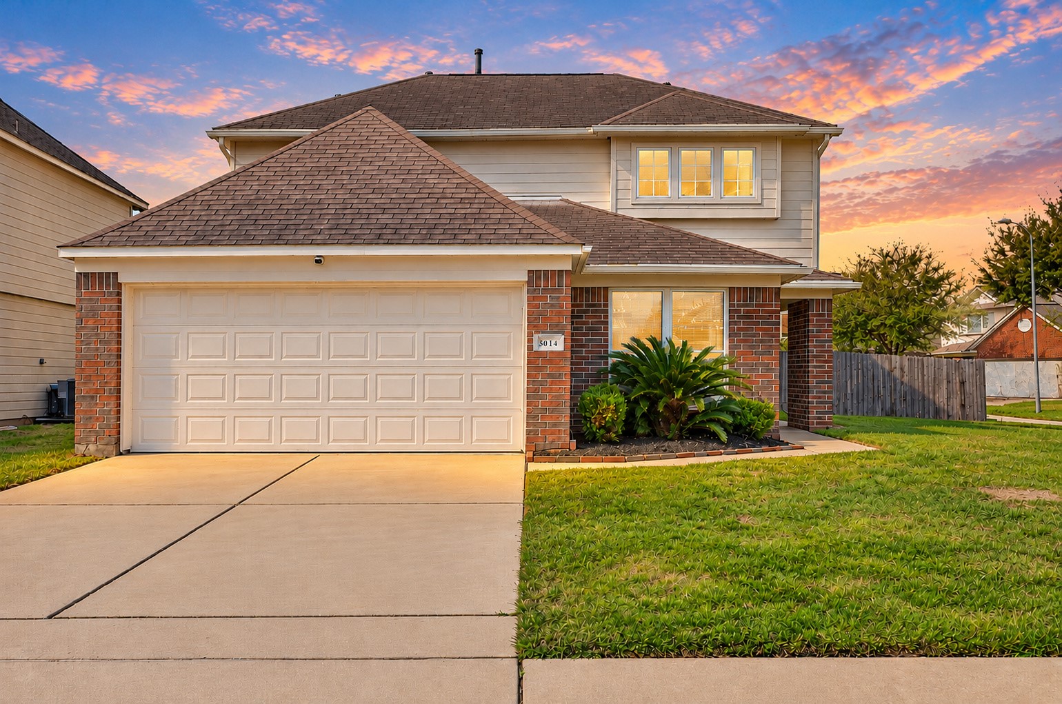 Welcoming front elevation featuring attractive brick and stone accents, an attached 2-car garage and a wide driveway.