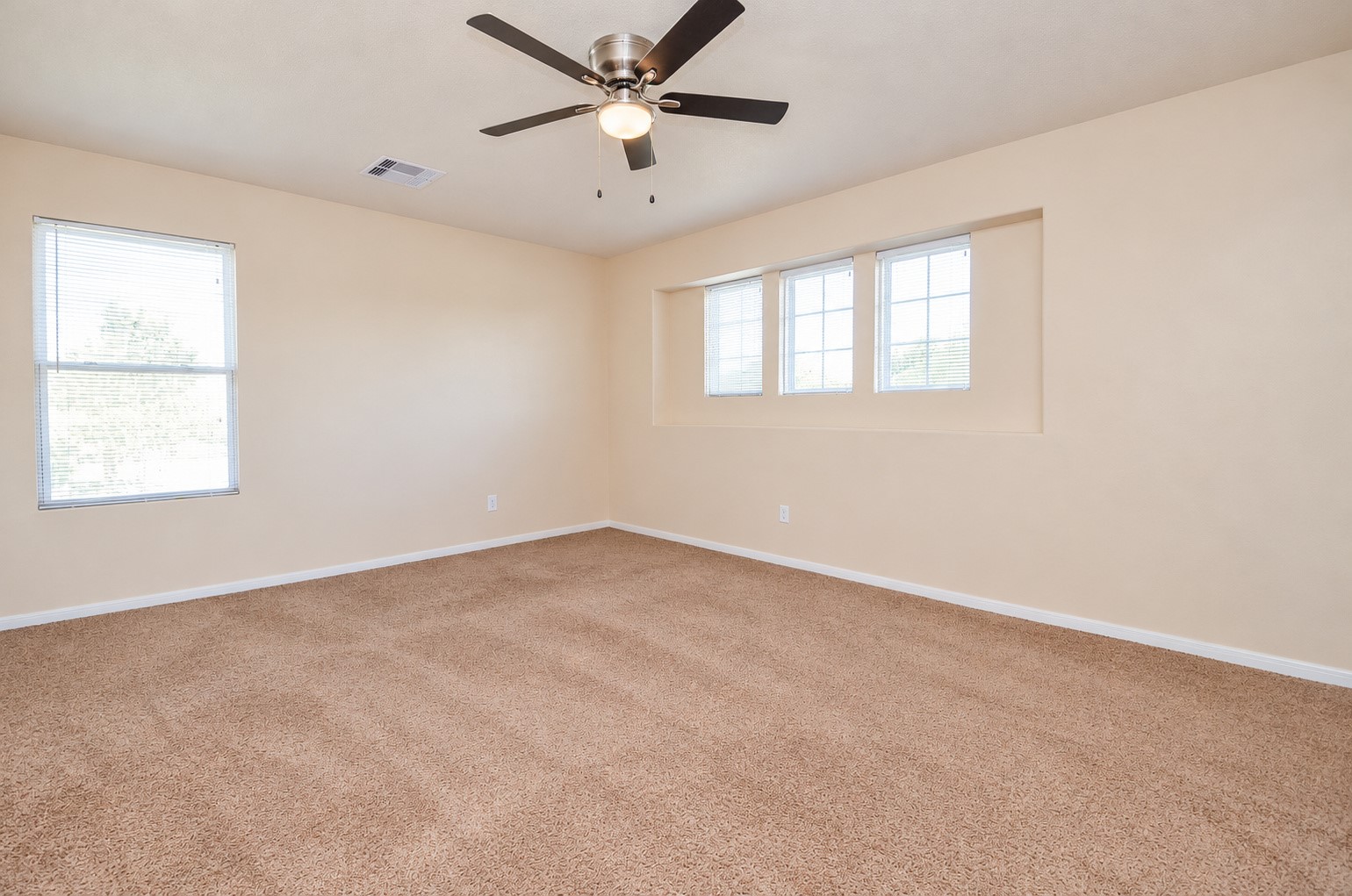 Oversized second-floor bedroom featuring a ceiling fan, neutral carpeting and abundant natural light. Ideal as an optional second primary bedroom.