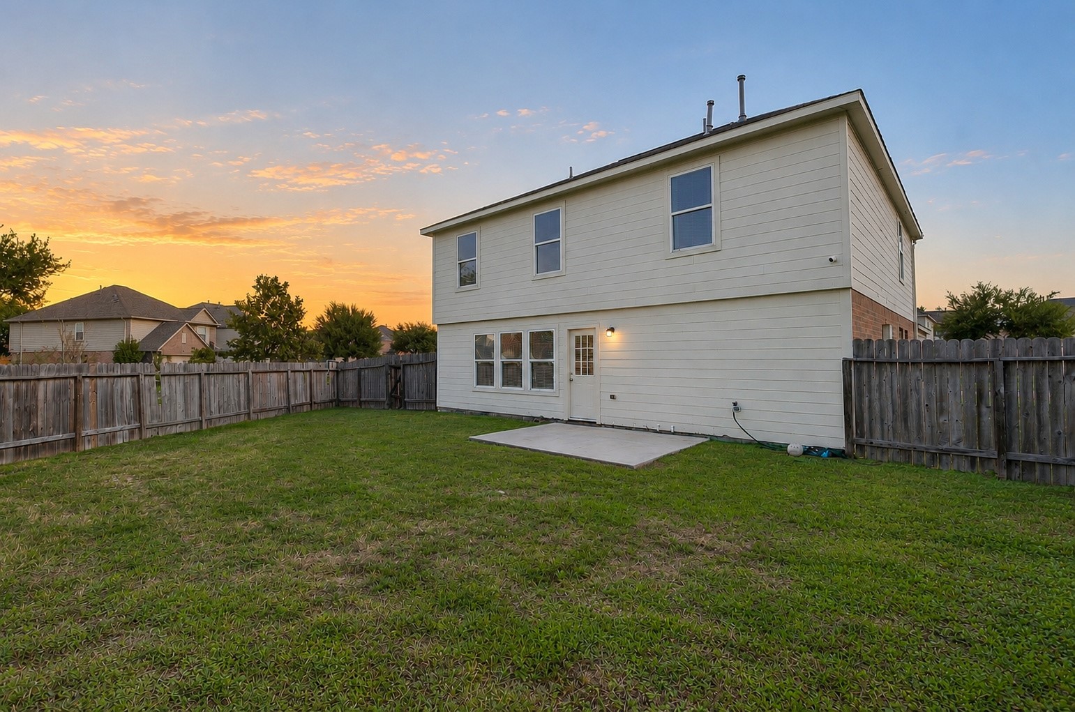 Rear exterior view showcasing the home's two-story design, spacious fenced backyard and generous outdoor space.