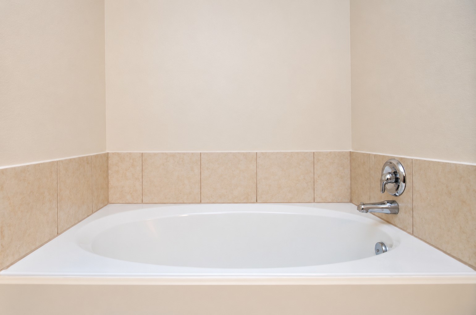 Relaxing soaking tub in the first-floor primary bathroom, featuring a tiled surround and separate shower nearby.