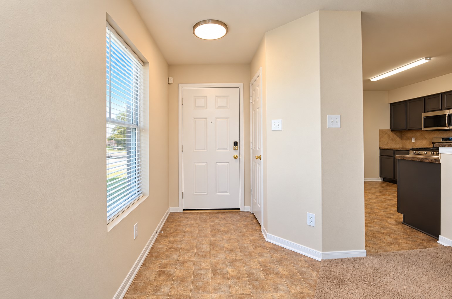 Welcoming entryway with natural light, neutral finishes and convenient access to the kitchen and main living areas.
