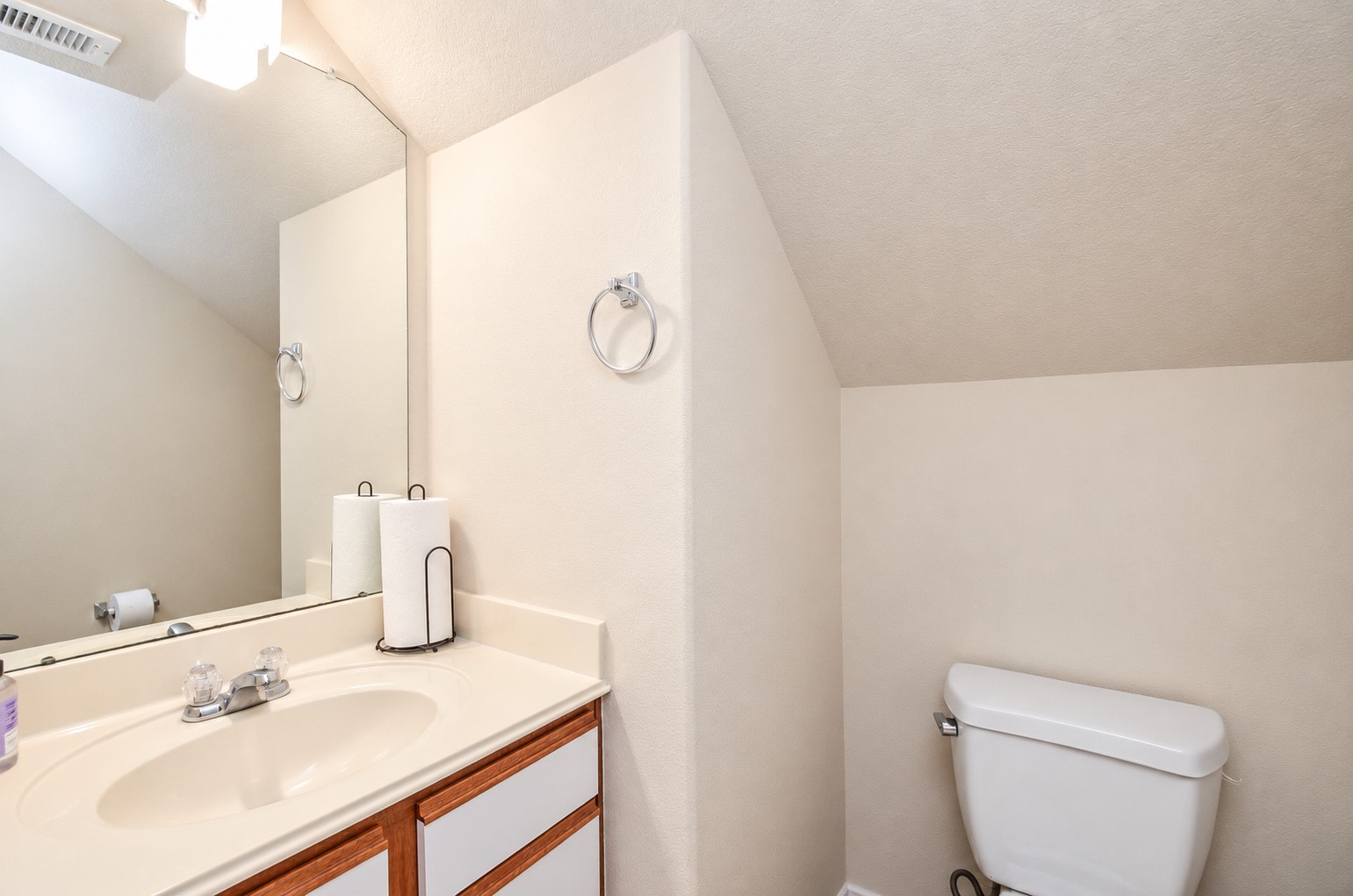 Convenient first-floor half bath featuring a vanity with ample counter space, large mirror and neutral finishes.
