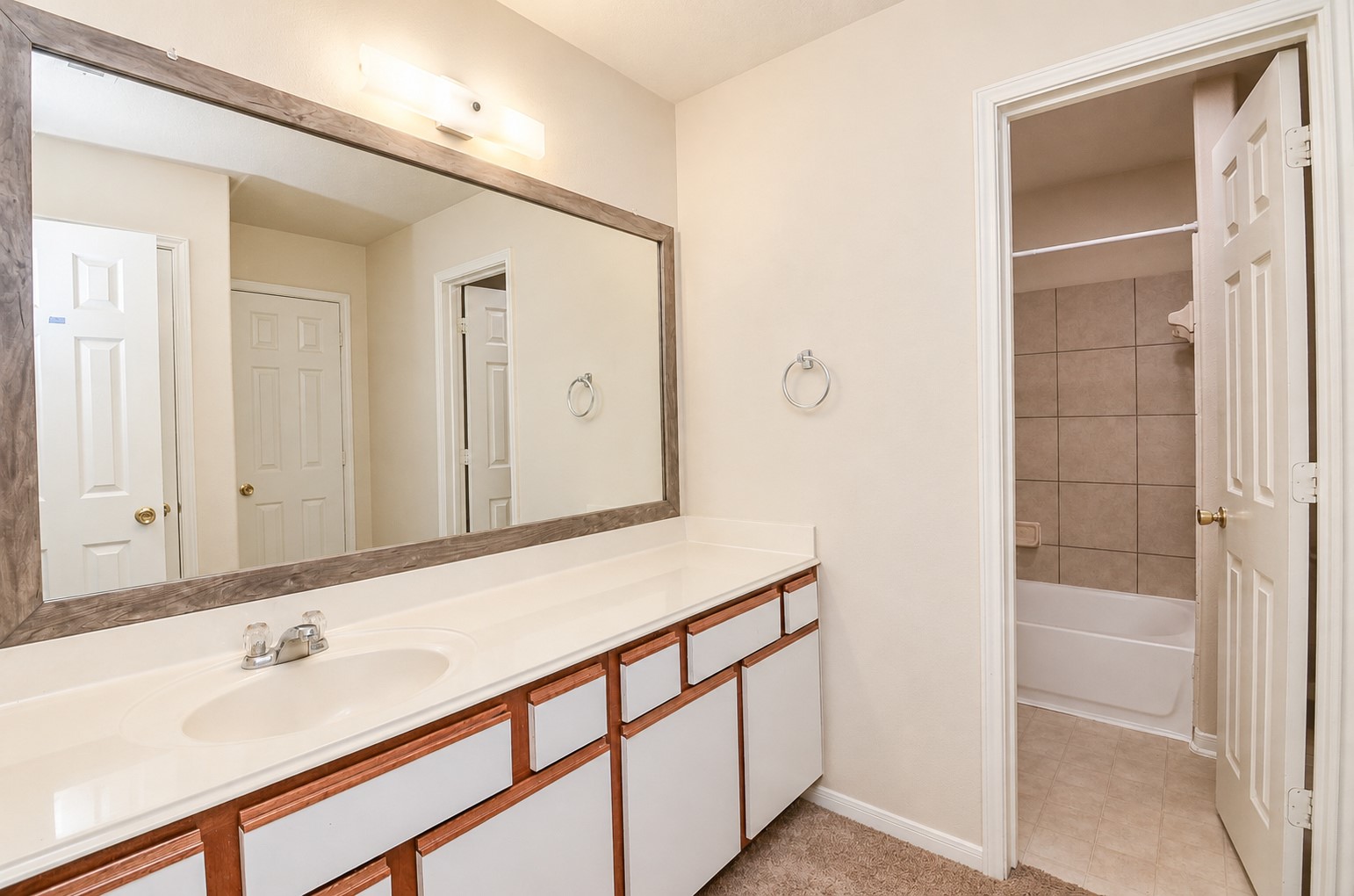 Spacious upstairs full bathroom featuring an extended vanity, large framed mirror and separate tub/shower area.