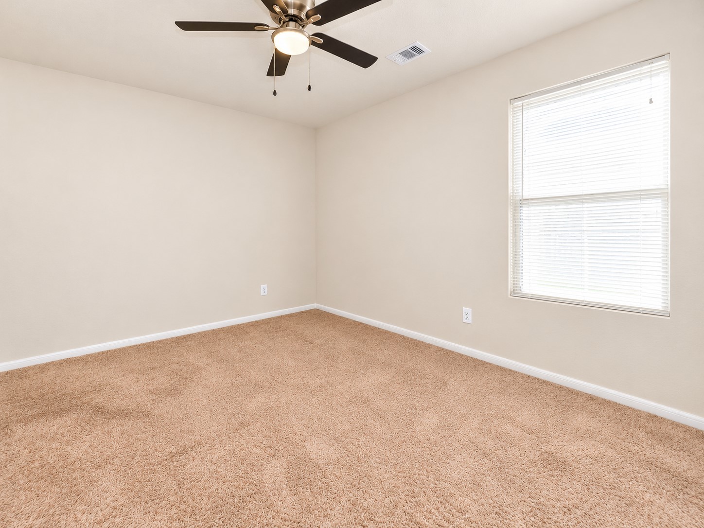 Third bedroom upstairs featuring neutral carpeting, a ceiling fan and a large window providing natural light.