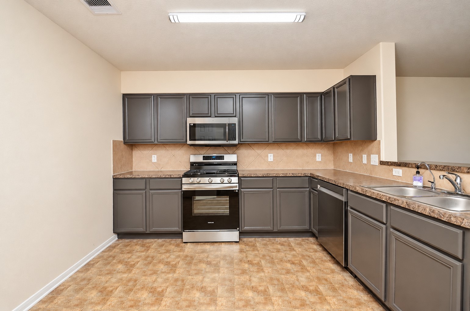 Well-appointed kitchen with gray cabinetry, stainless steel appliances, gas range and abundant countertop space.