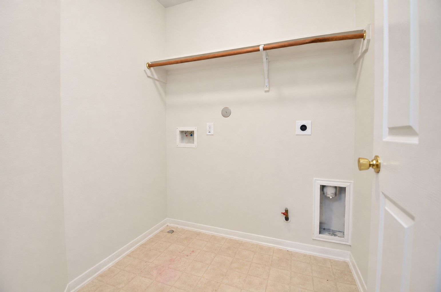 Convenient second-floor laundry room with washer and dryer connections, overhead shelving and hanging rod, located near the upstairs bedrooms.