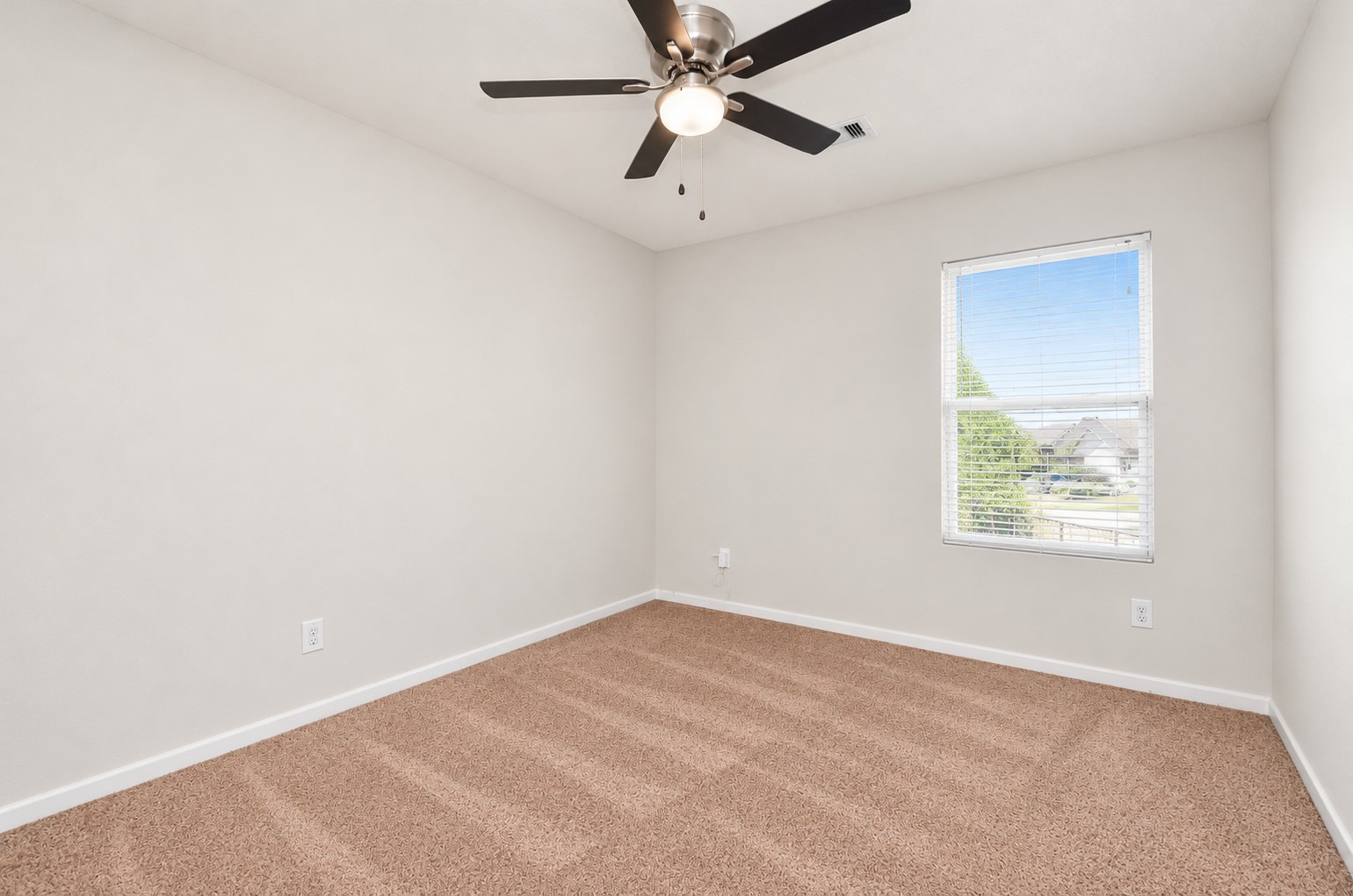 Fourth bedroom upstairs featuring neutral carpeting, a ceiling fan and a window providing natural light.