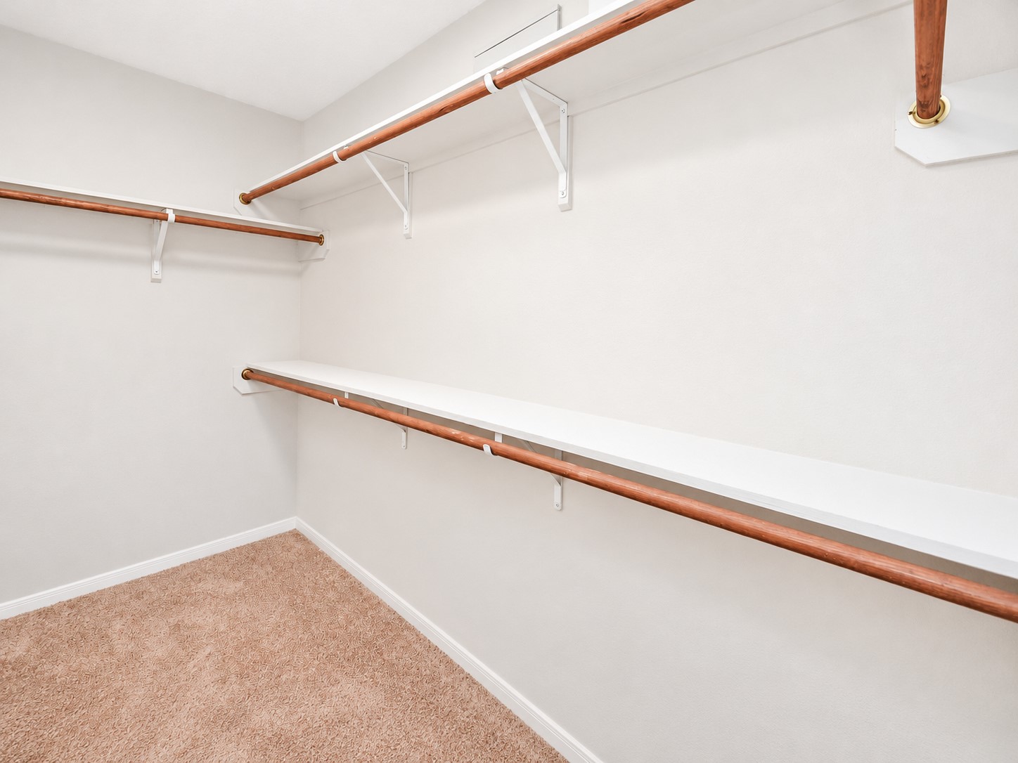 First-floor primary walk-in closet featuring multiple hanging rods and shelving for convenient storage and organization.