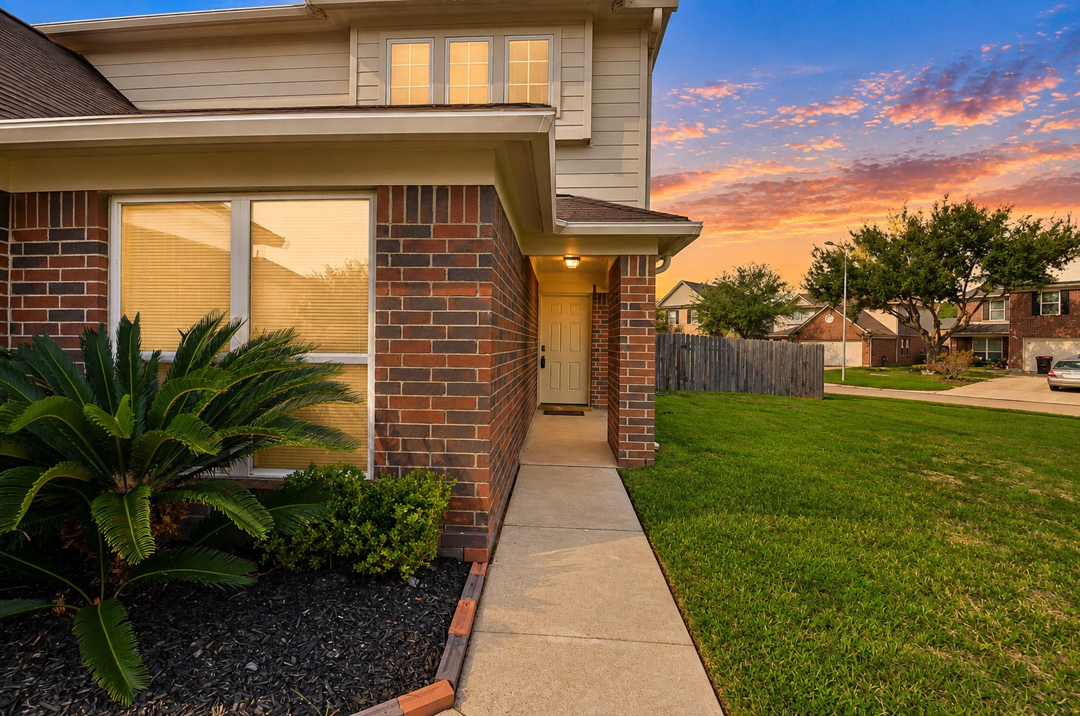 Side view showcasing the home's brick exterior, manicured landscaping and spacious yard.