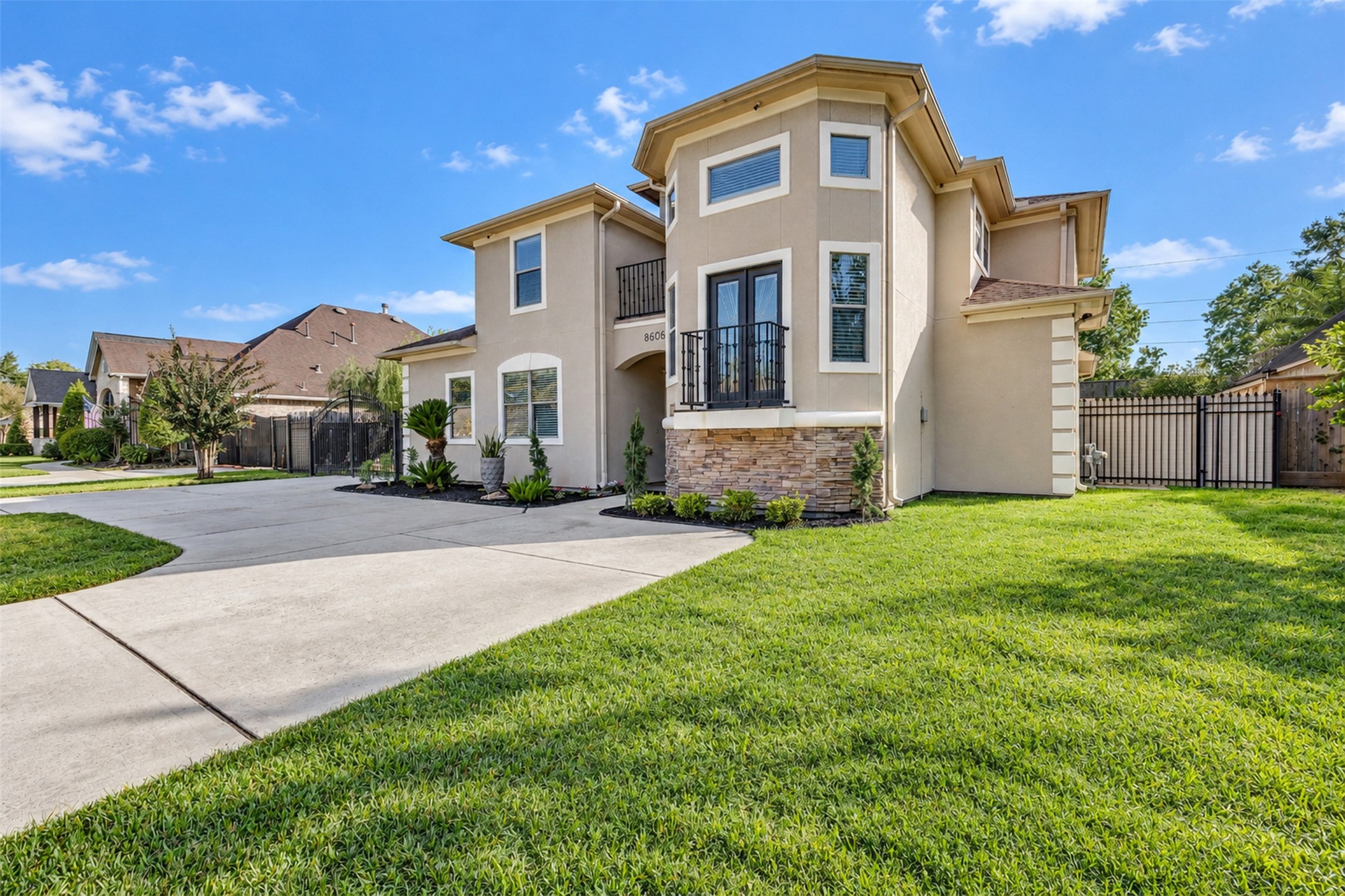 Front Exterior: Distinctive two-story architecture with an elegant stucco faade, stone accents, and two balconies that create striking curb appeal.