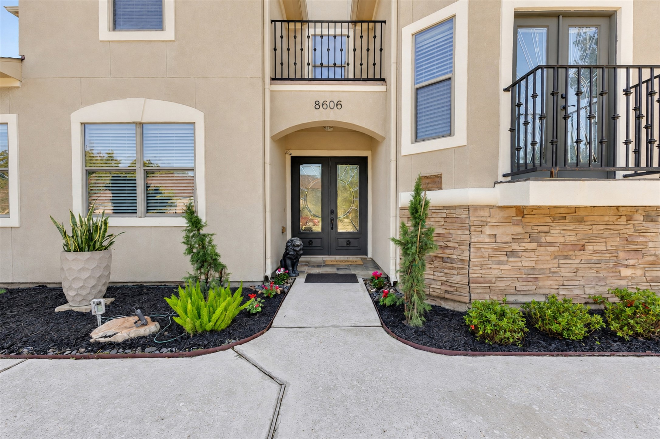 Front Exterior: Distinctive two-story architecture with an elegant stucco faade, stone accents, and two balconies that create striking curb appeal.