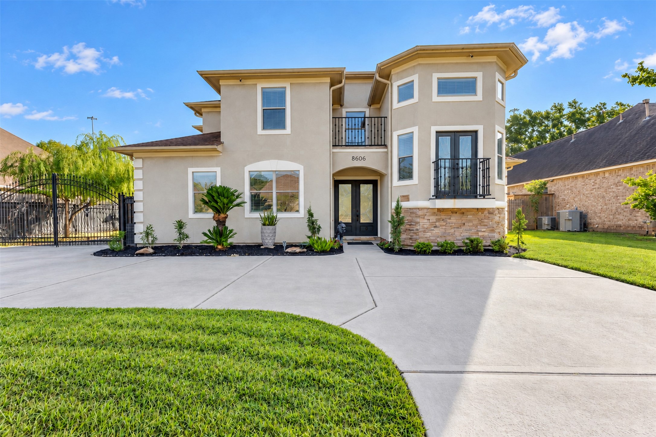 Striking curb appeal with an elegant stucco and stone exterior, two charming balconies, and a gated driveway. Double entry doors create a welcoming first impression.