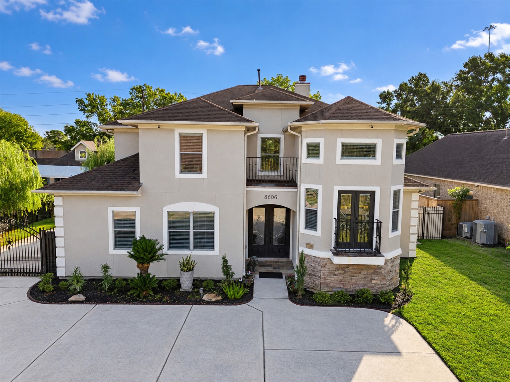 Distinctive two-story architecture with a sophisticated stucco exterior and contrasting stone accents.