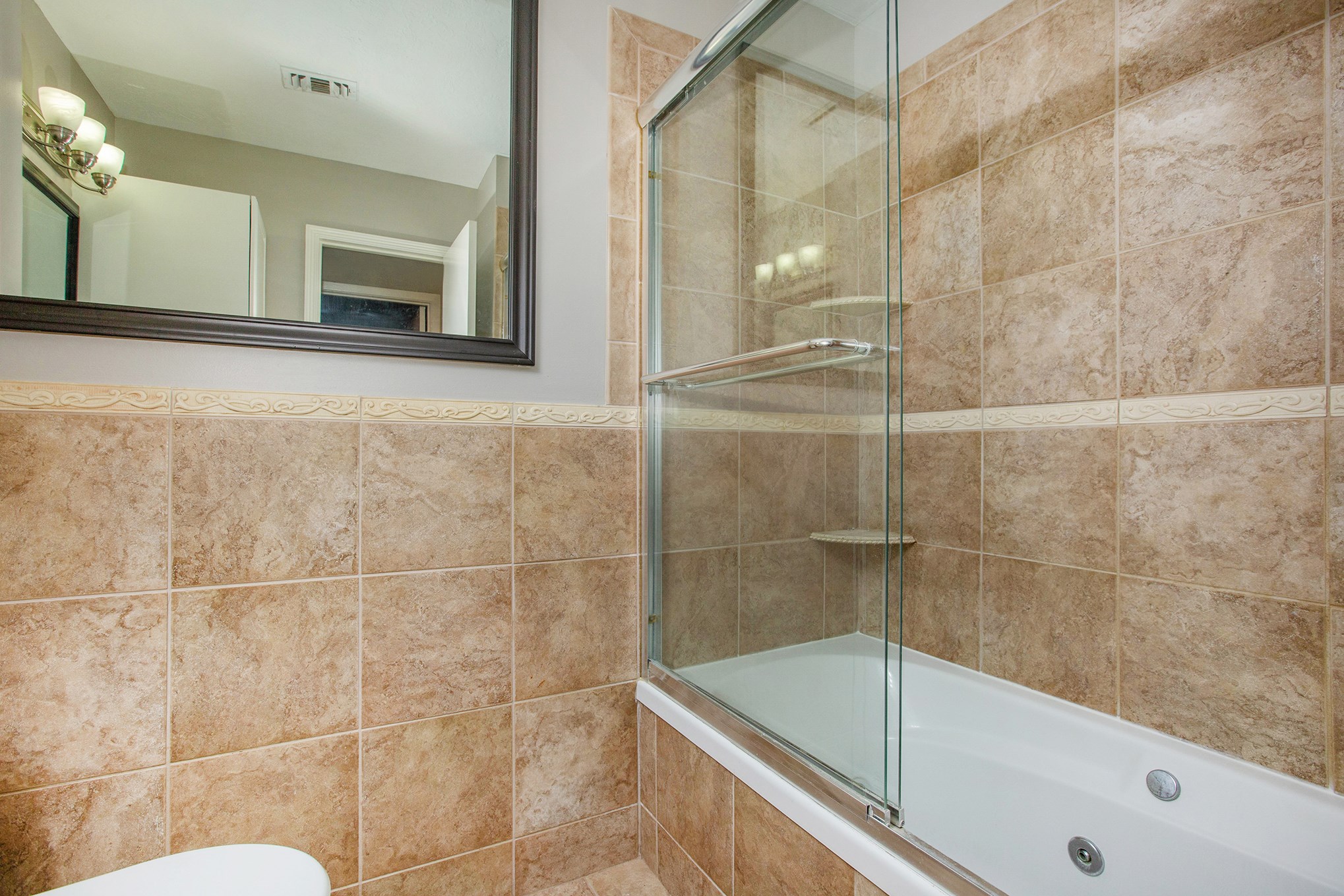 Guest bathroom features granite countertop, framed mirror, tub/shower combination with whirlpool jets.