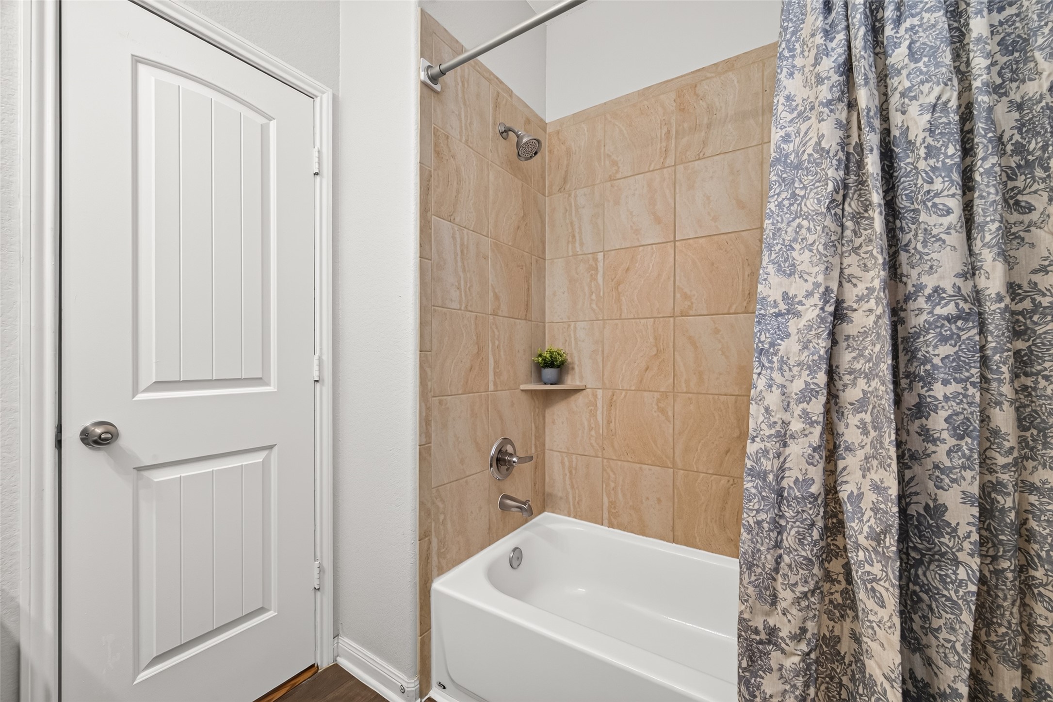 A closer look at the tub and shower combination, complete with surrounding ceramic tile.
