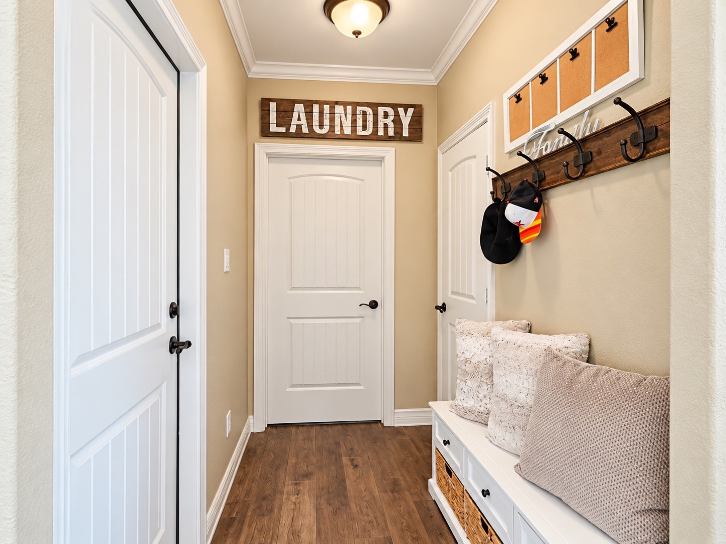Charming mudroom featuring a cozy bench with storage baskets, wall hooks for convenience, and an inviting entry to the laundry area.