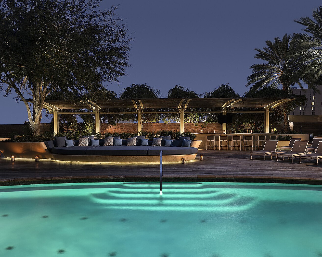 Resort-style pool with dramatic evening lighting and cabana seating for entertaining or relaxing under the stars.