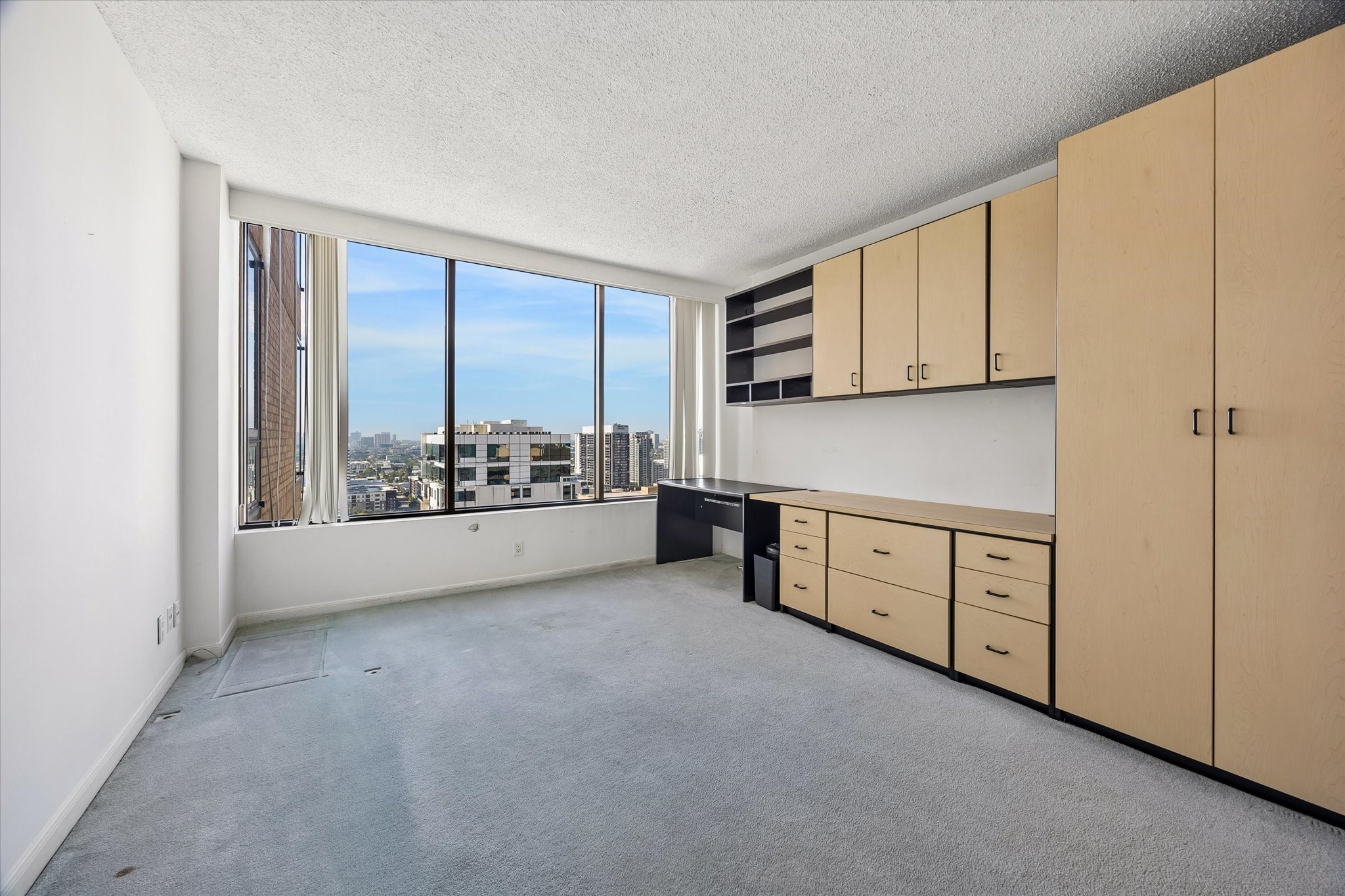 Built in cabinetry and a desk beside the window create a dedicated place to work with a
city view. Upper cabinets, drawers and tall storage keep work materials organized while leaving the surrounding floor area open.