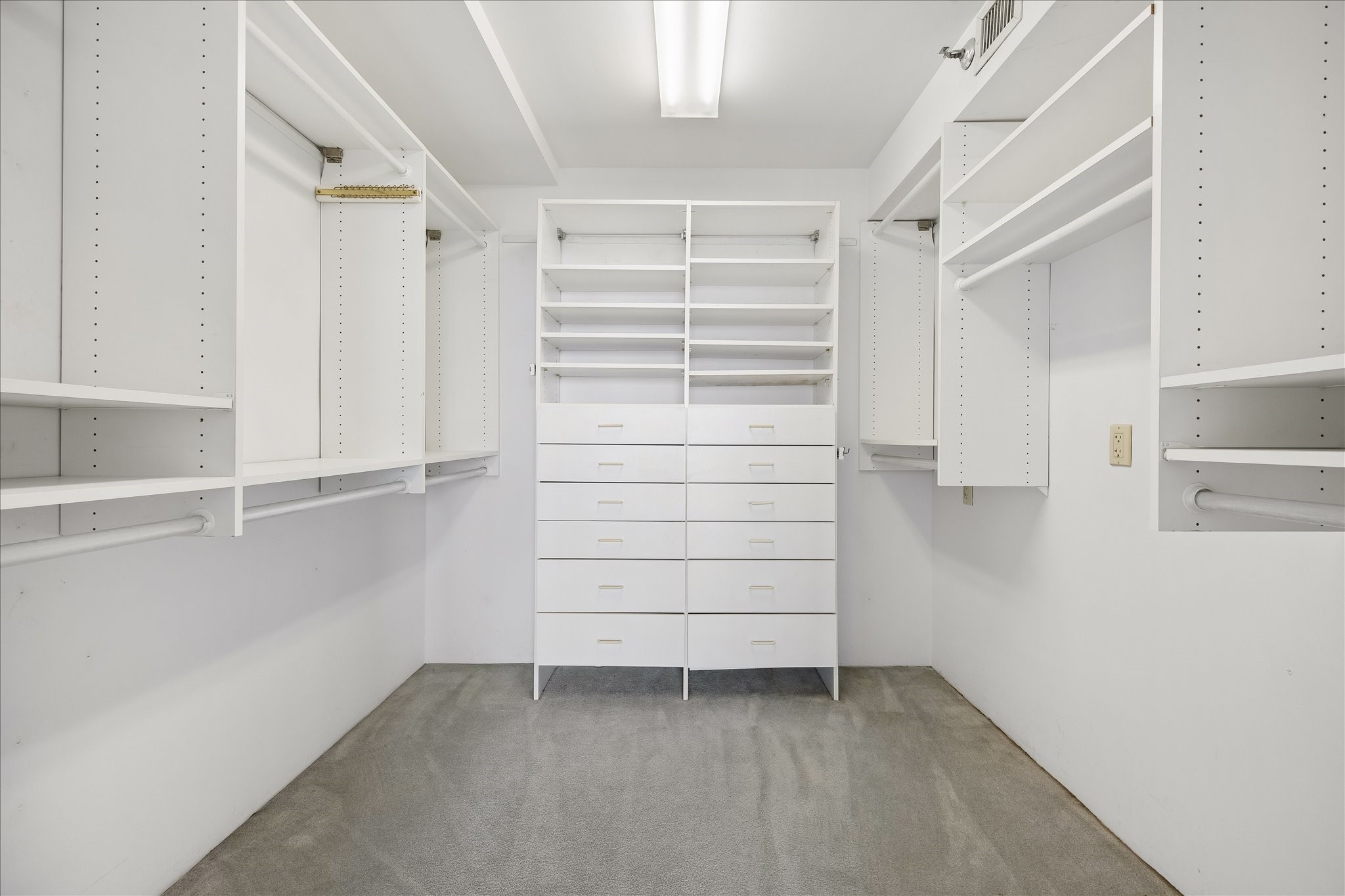 Hanging rods, open shelving and a central bank of drawers bring structure to the walk in closet. Dedicated areas for clothing, shoes and accessories make it easy to organize daily essentials.