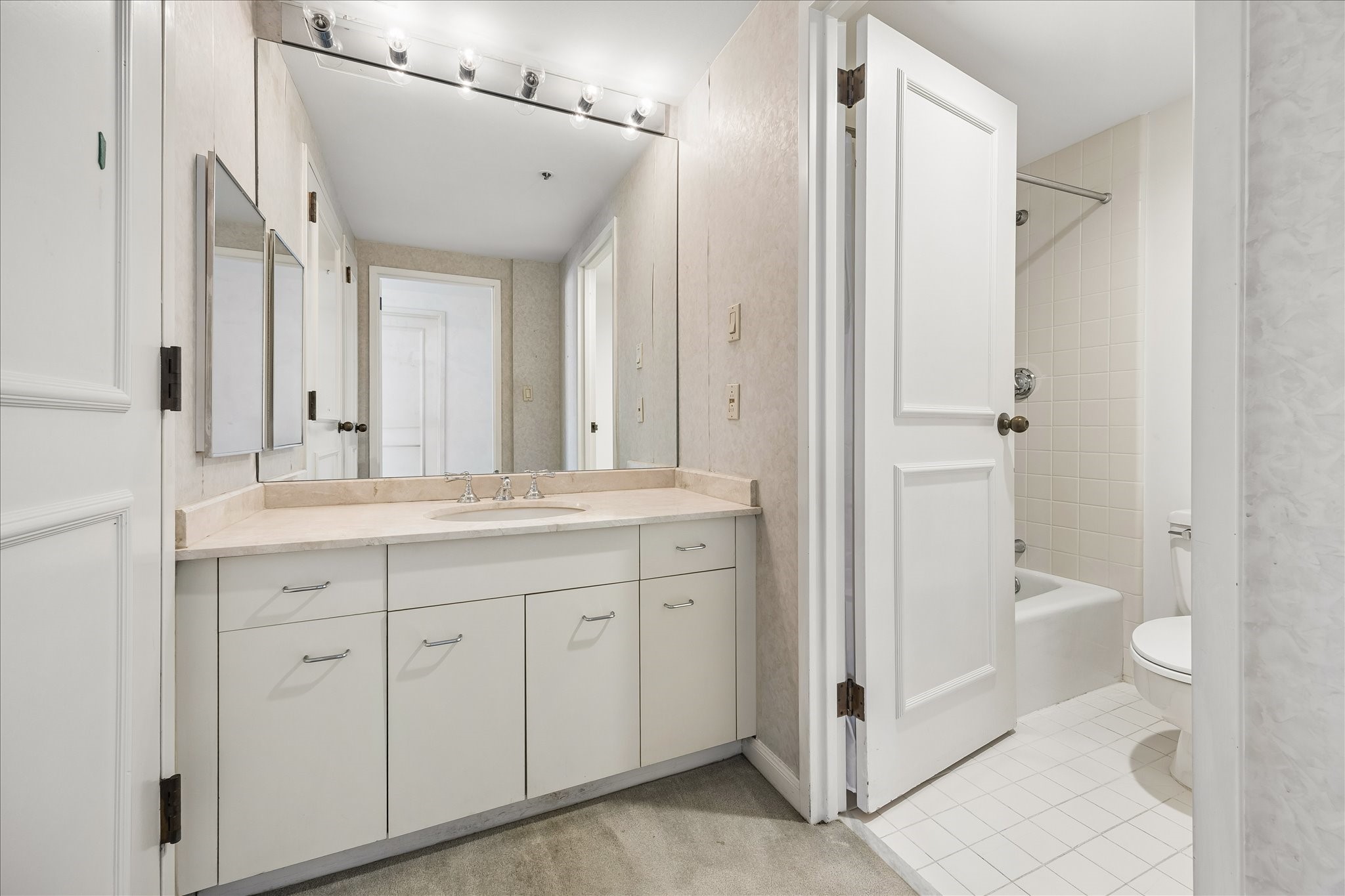 Separate vanity and bathing areas provide added flexibility for daily routines. A wide counter,
mirrored wall and lower cabinets offer storage and preparation space, with a tub and shower combination beyond.