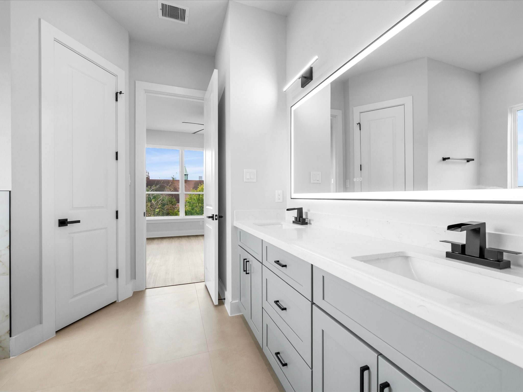 Contemporary lighting, elegant finishes, and clean lines give the primary bathroom vanity a polished look that complements the home's sophisticated design.